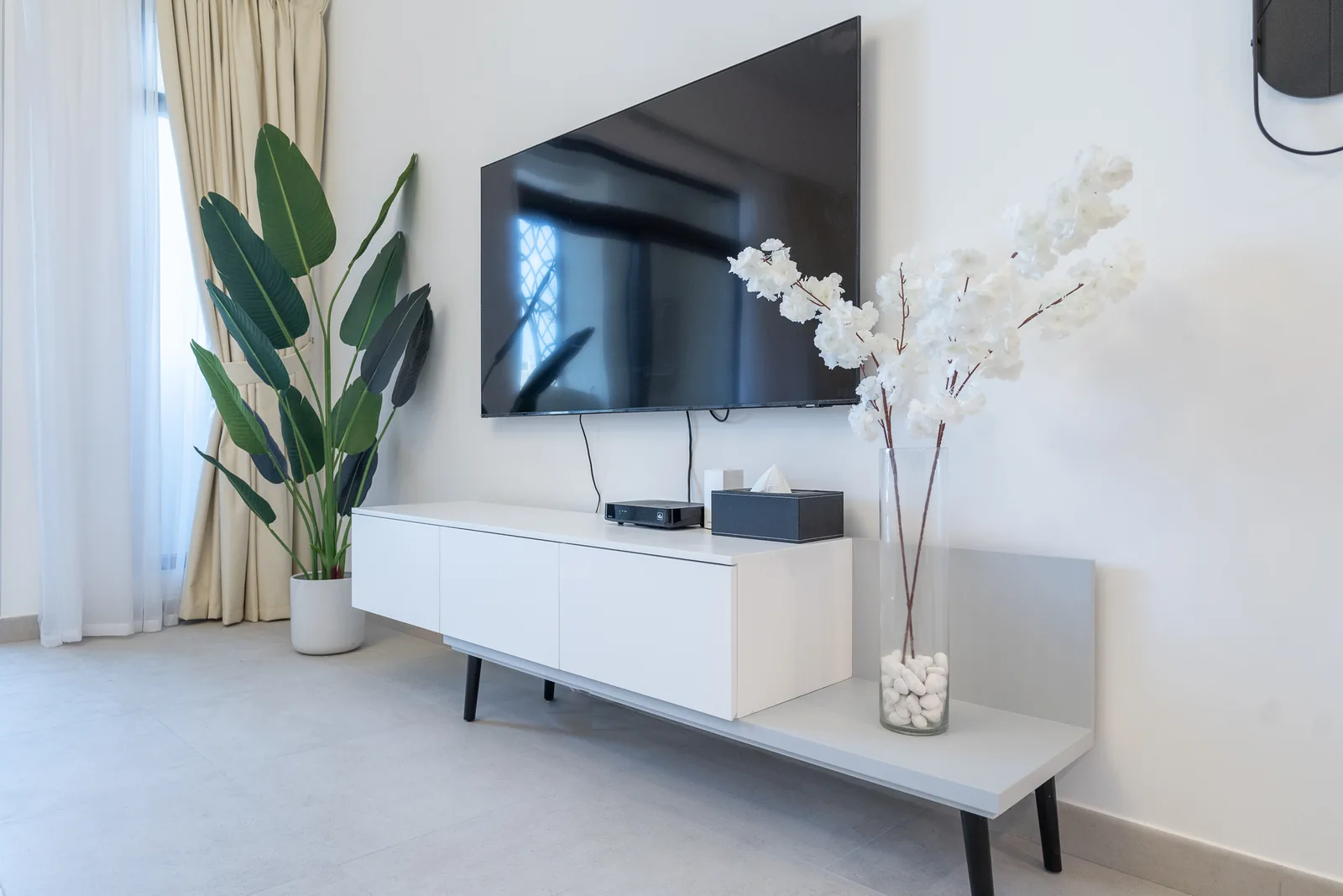 White low media console below a wall-mounted television.