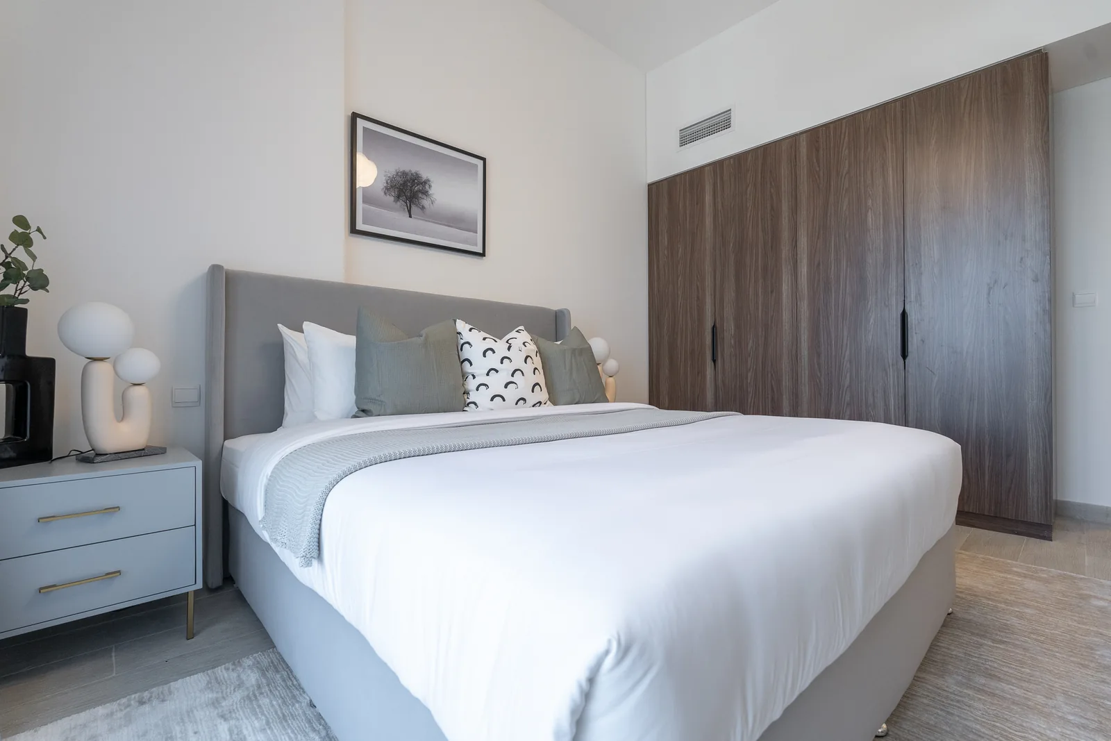 Bedroom seen from the other side, with a timber-toned wardrobe and bedside cabinet.