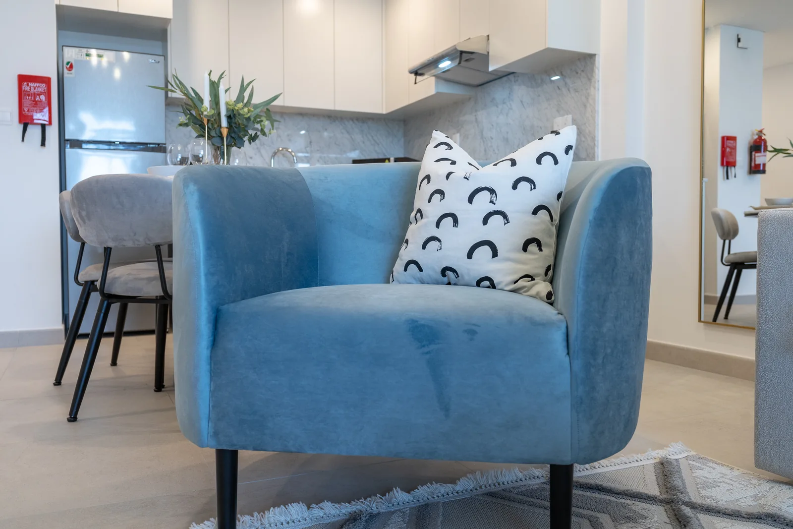 Blue upholstered accent chair with a patterned cushion.