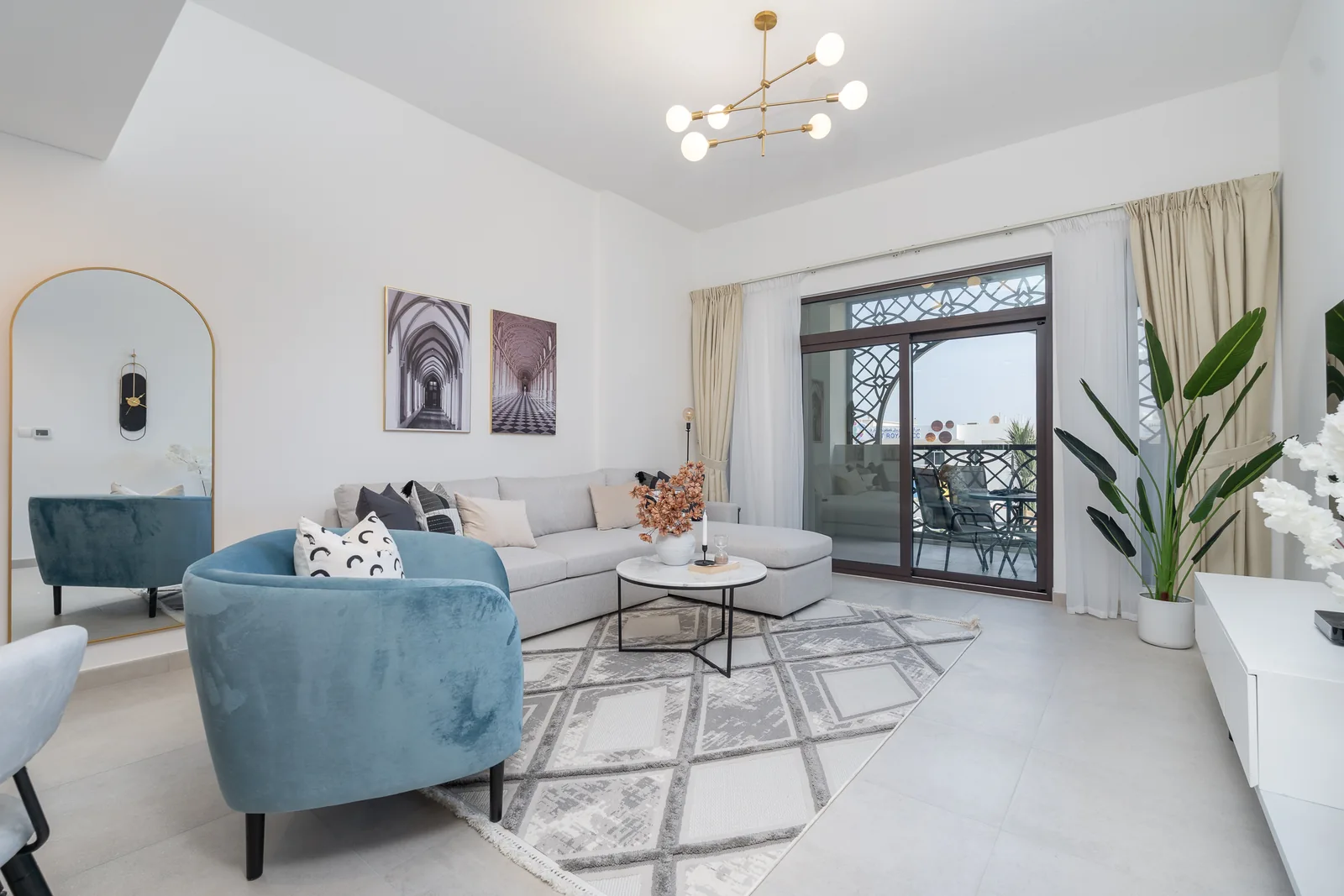 Wider view of the living room with a sculptural ceiling light and seating facing the balcony doors.