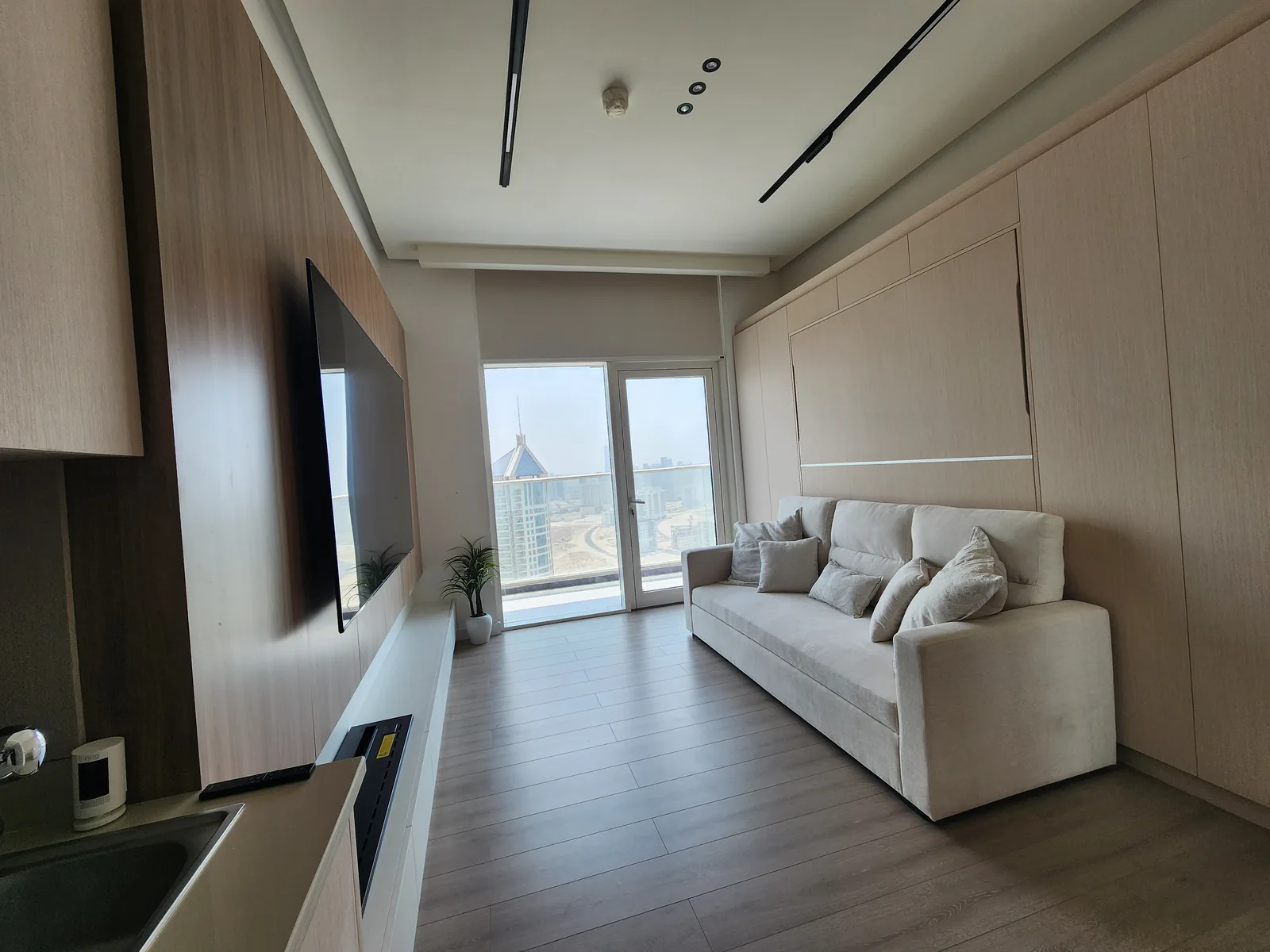 Compact living room with a sofa, pale wall panels and a television wall.