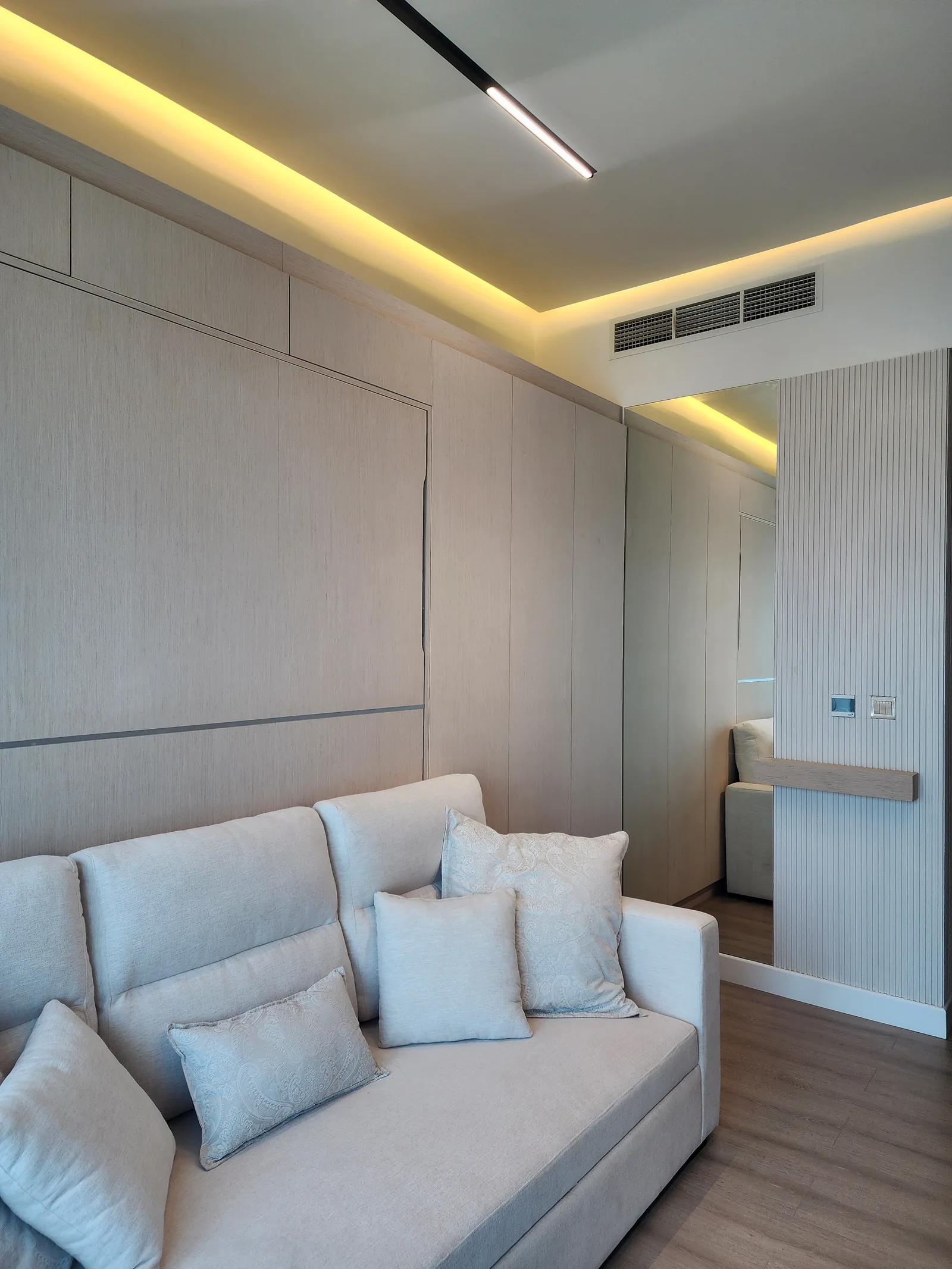 Pale upholstered sofa against full-height pale wall panelling.