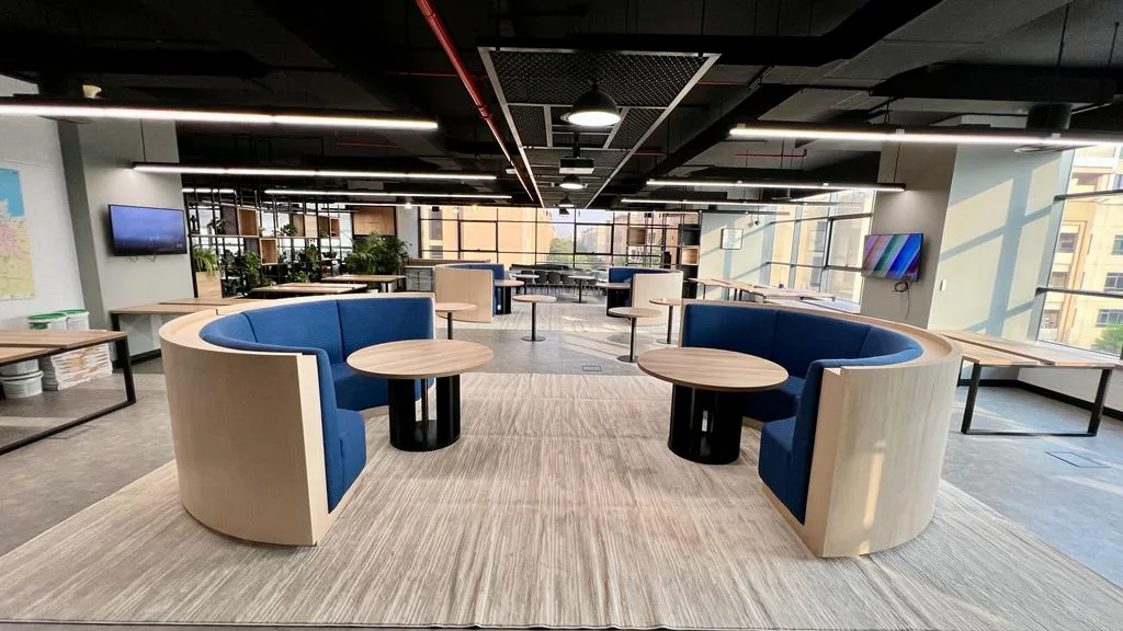 Two curved blue seating booths facing round tables in a shared interior.
