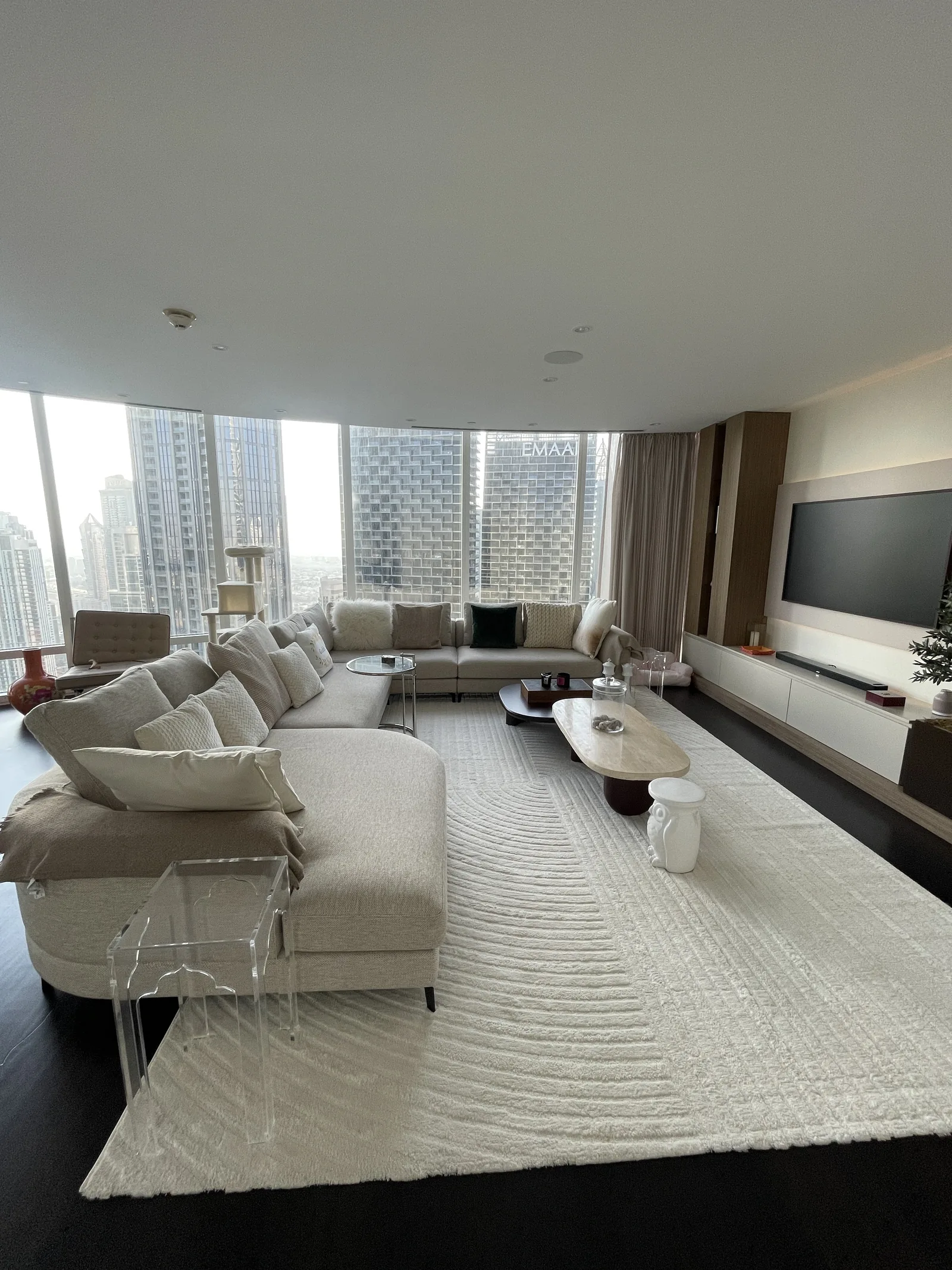 Room overview with curved sectional, media wall and nested tables.