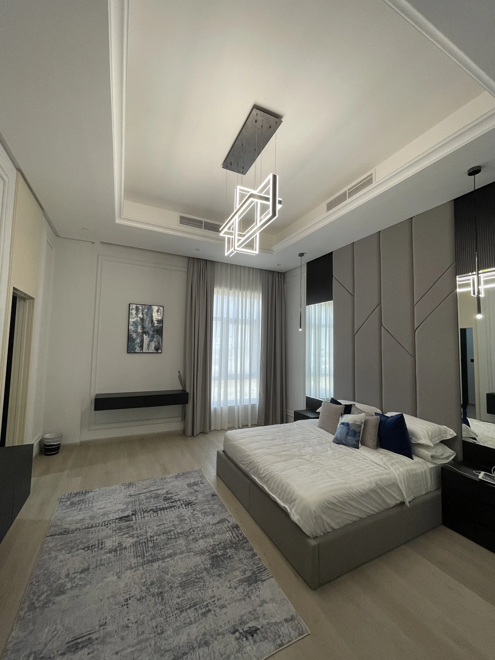Bedroom overview with geometric headboard and illuminated pendant.
