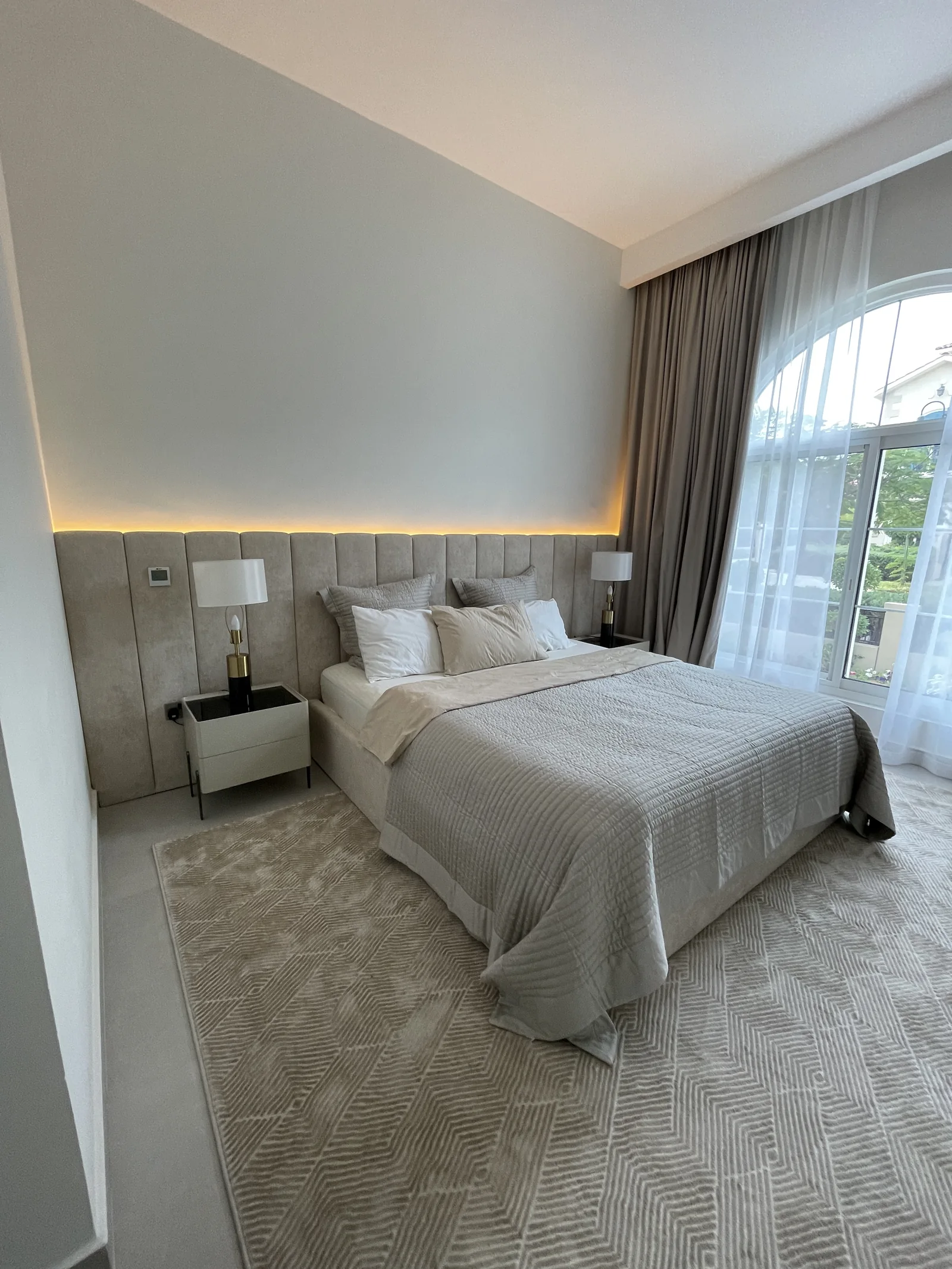 Upholstered bed, wall-wide channel headboard and integrated lighting.