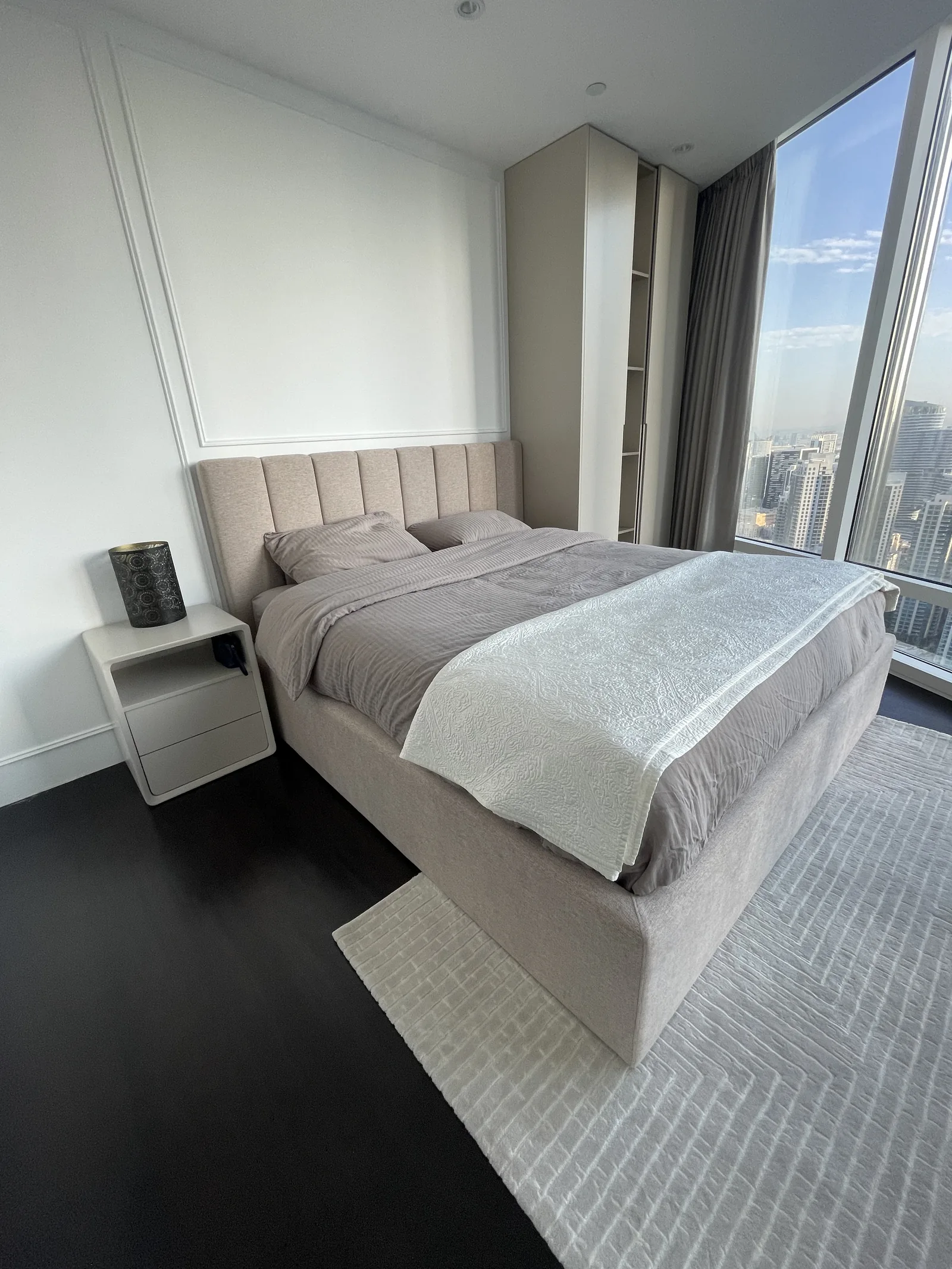 Bed, upholstered headboard and tall fitted bedside storage.