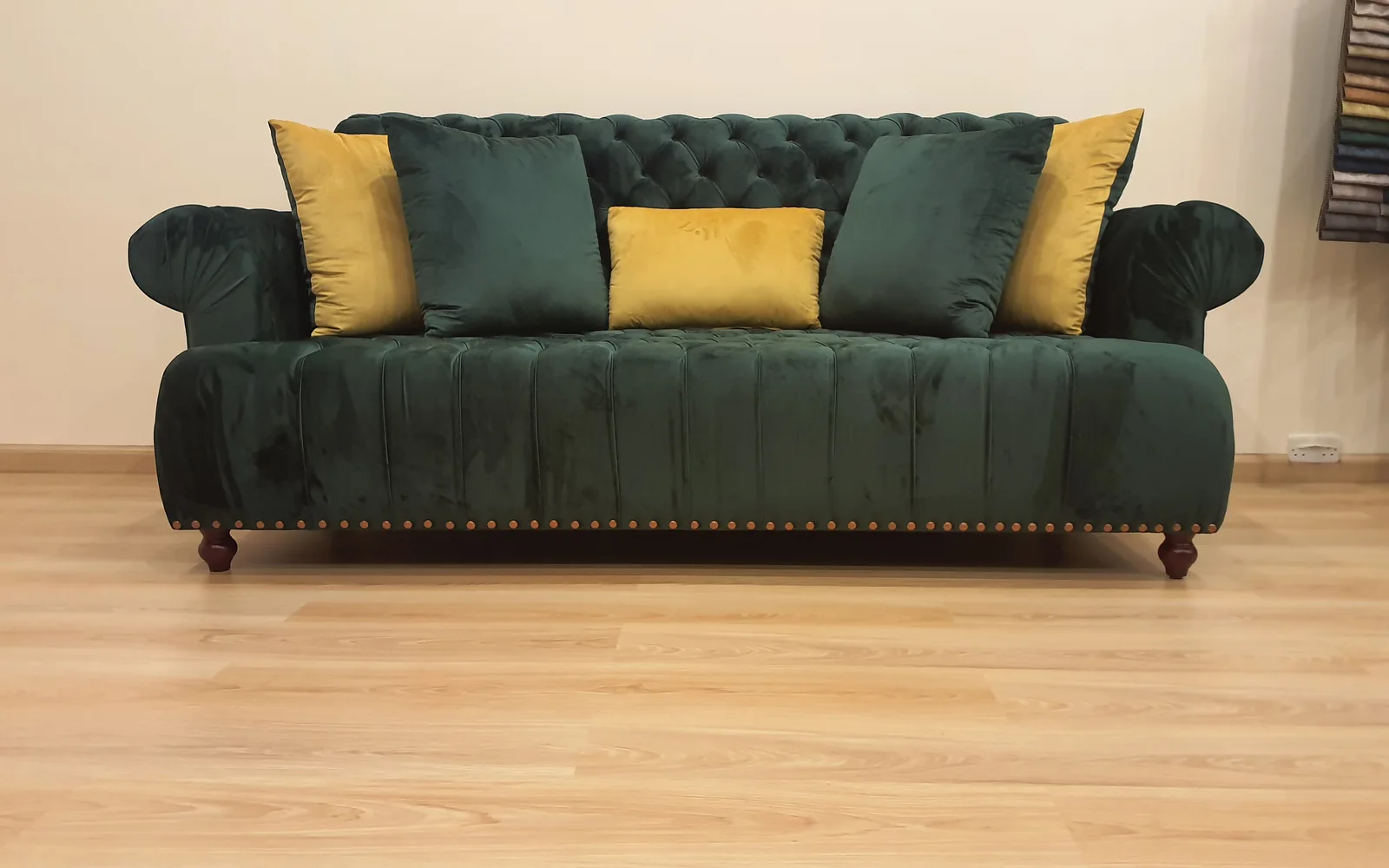 Deep green upholstered sofa with contrasting scatter cushions.