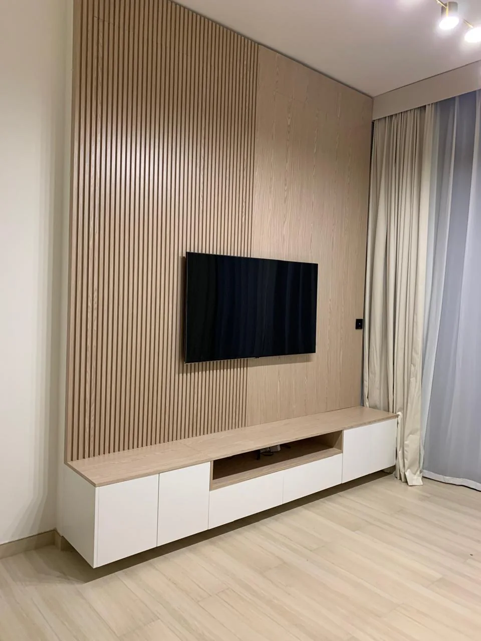 Slatted timber-toned TV wall and white low media console.