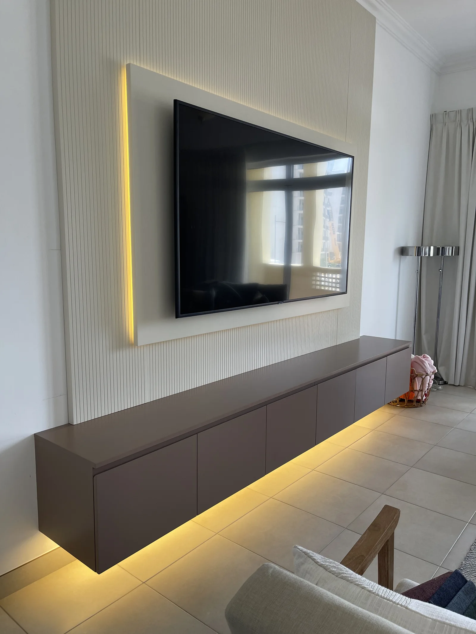 Wall-mounted console and finely fluted illuminated television panel.
