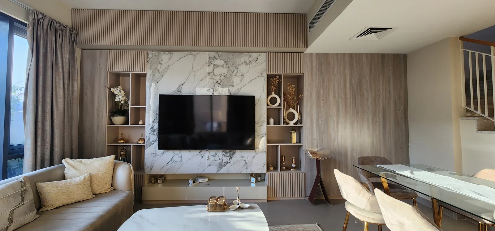 Living and dining area with a fluted TV wall, veined centre panel and display shelves.
