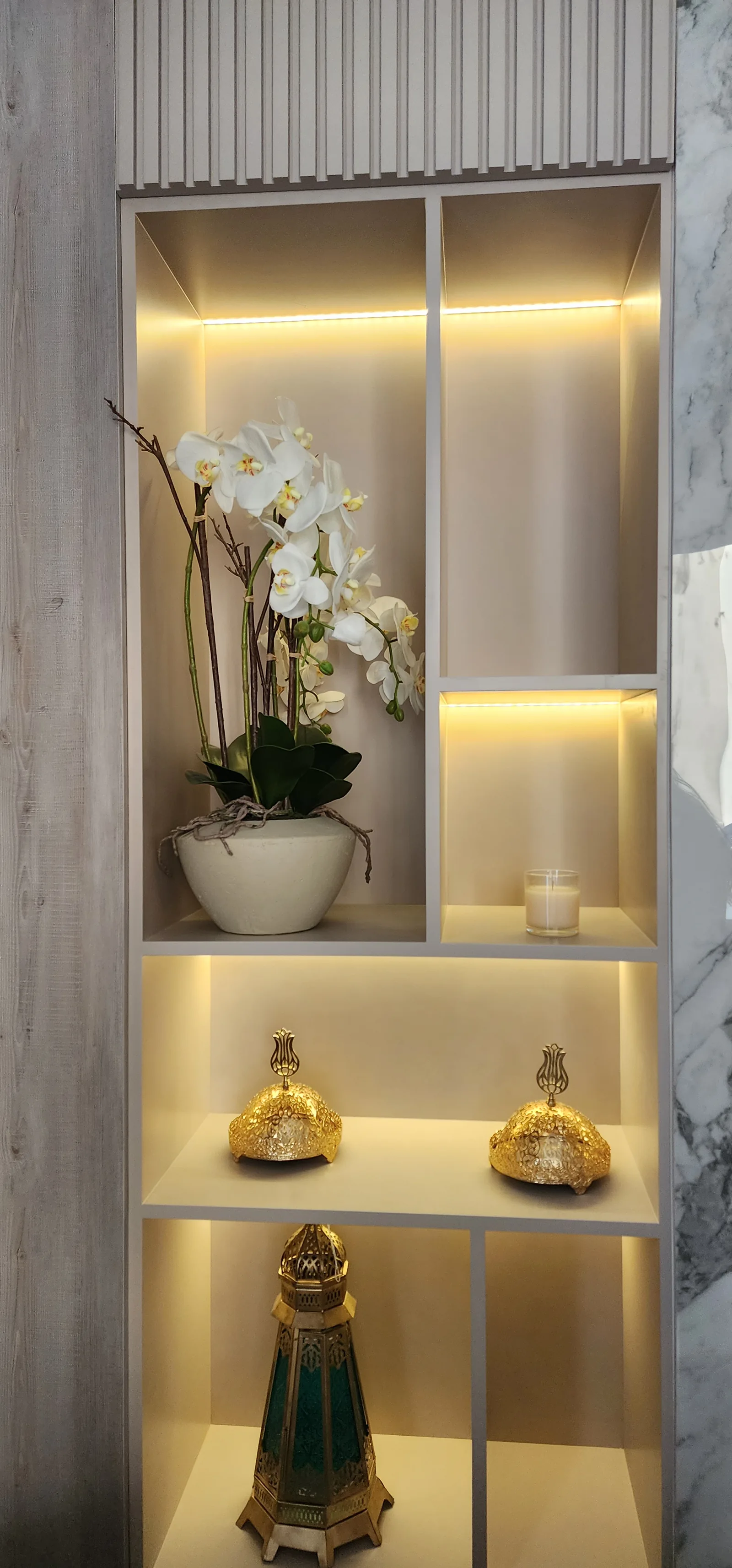 Tall illuminated display shelves with flowers and decorative objects.