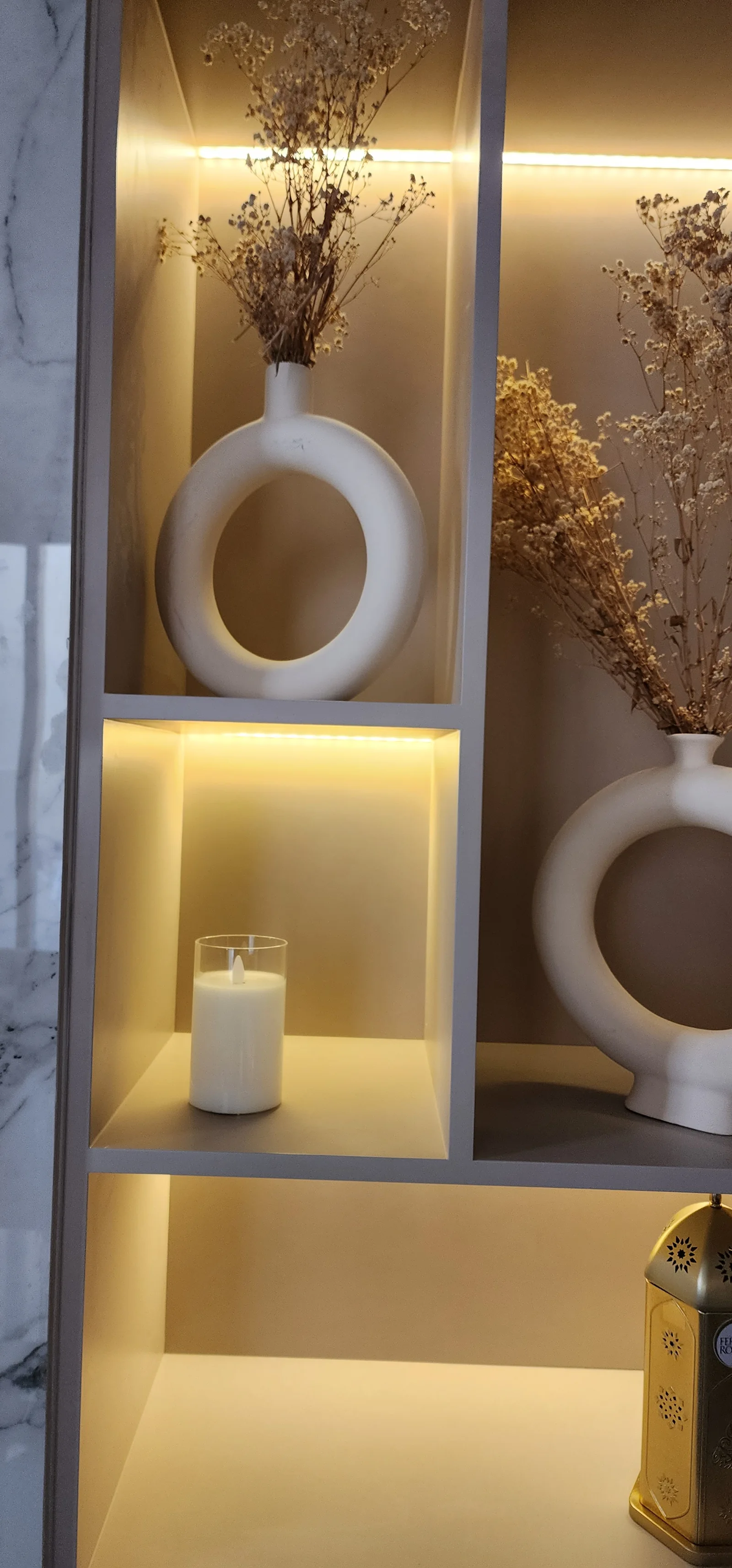 Close view of illuminated geometric shelving and circular ceramic vessels.