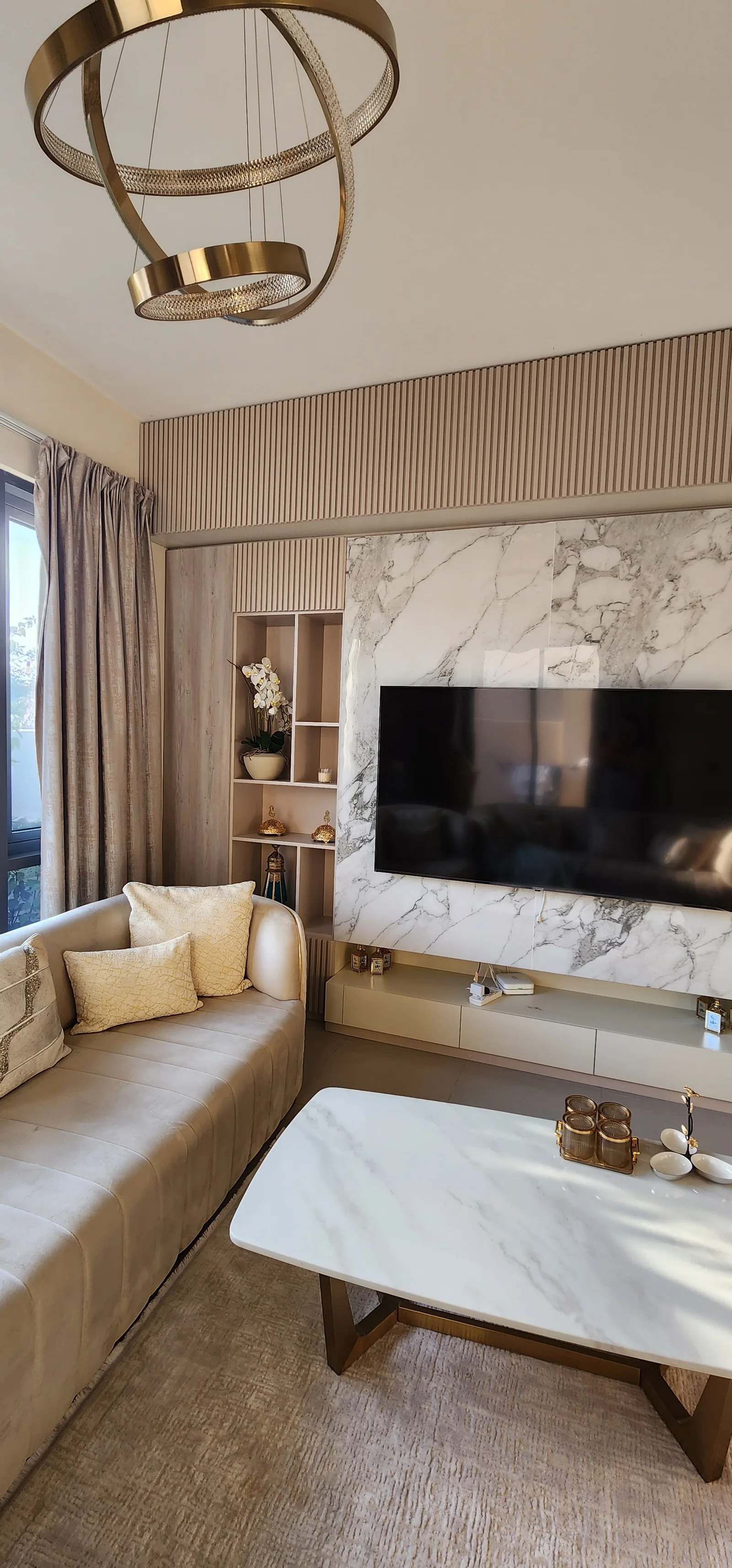 Portrait living vignette with coffee table, curved sofa and TV-wall joinery.