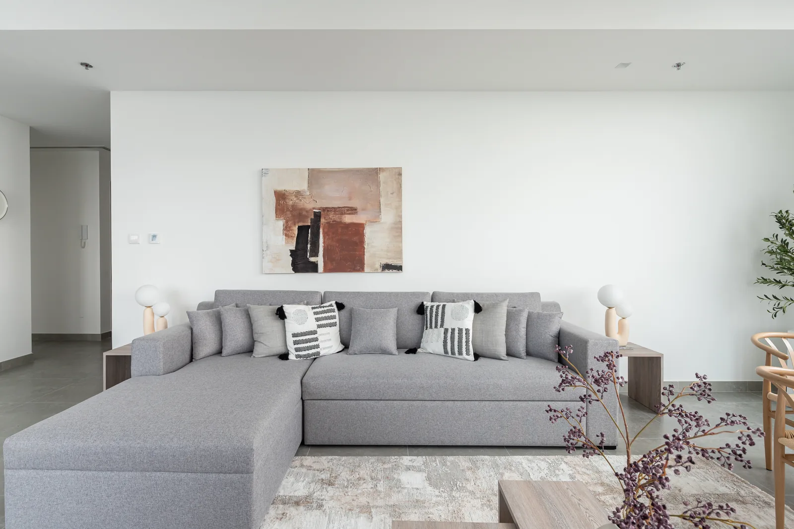 Grey sectional sofa and paired sculptural lamps.