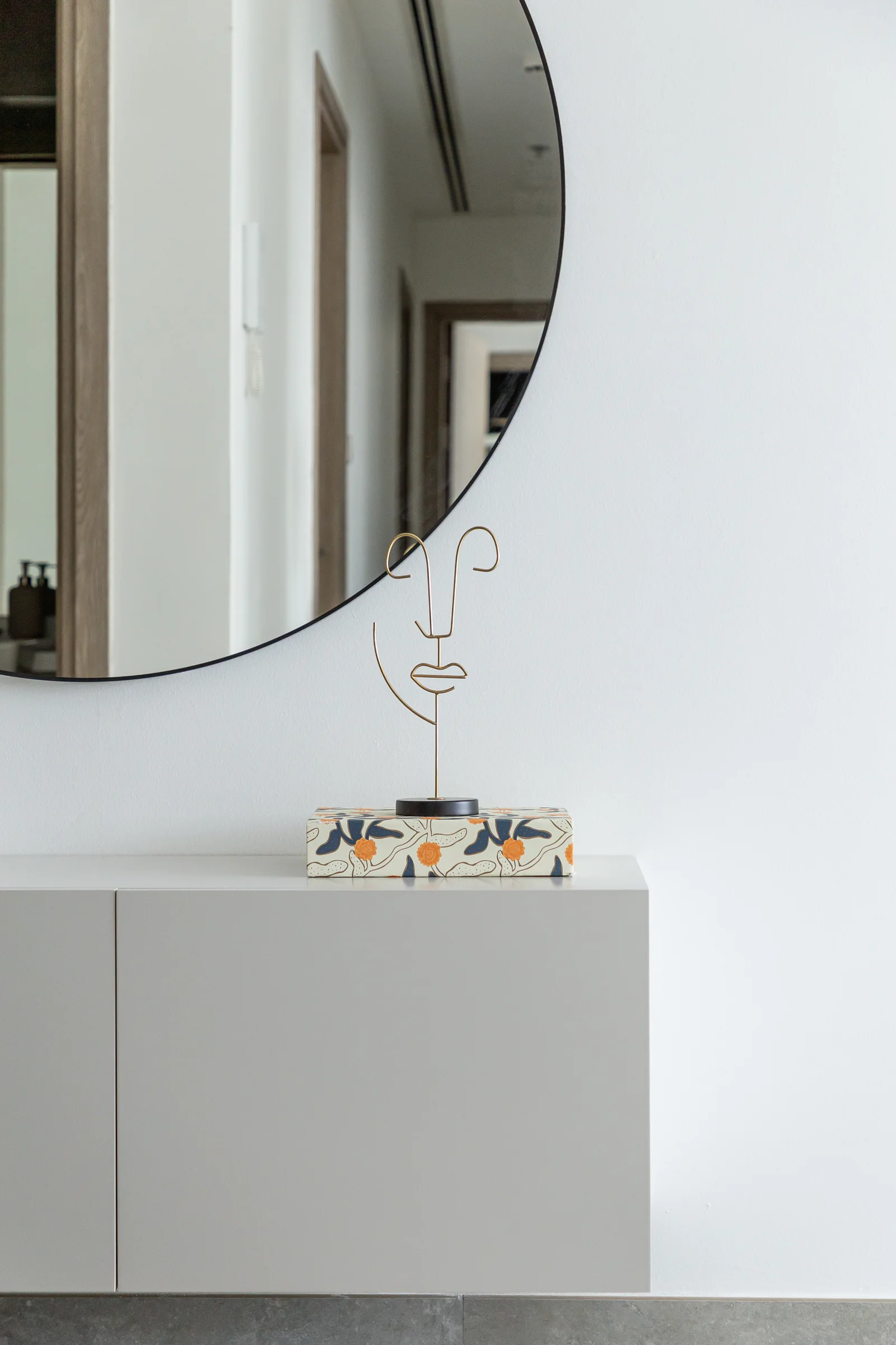 Entry console with wire sculpture and round mirror.