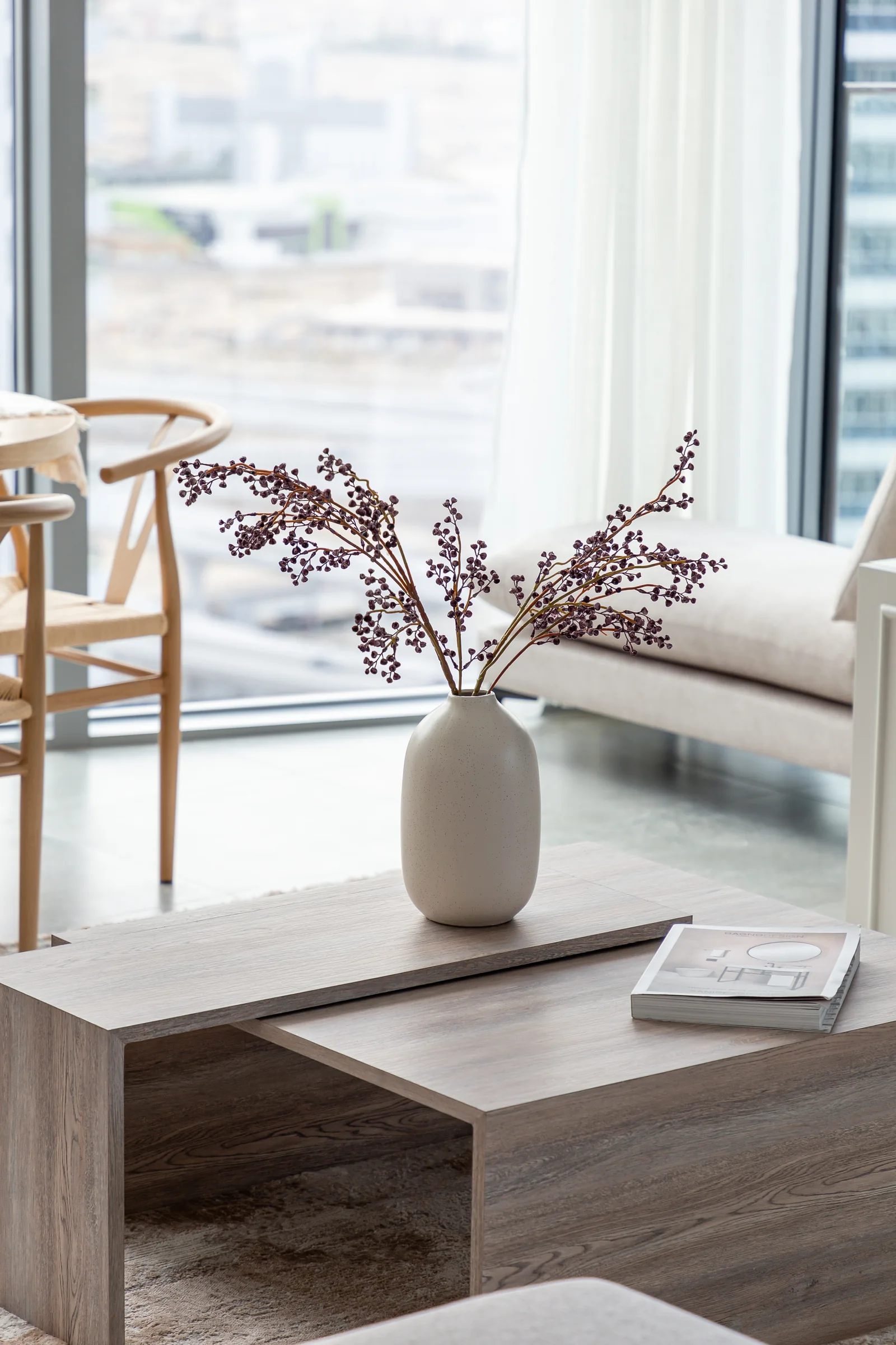 Nesting timber-toned coffee tables and vase.