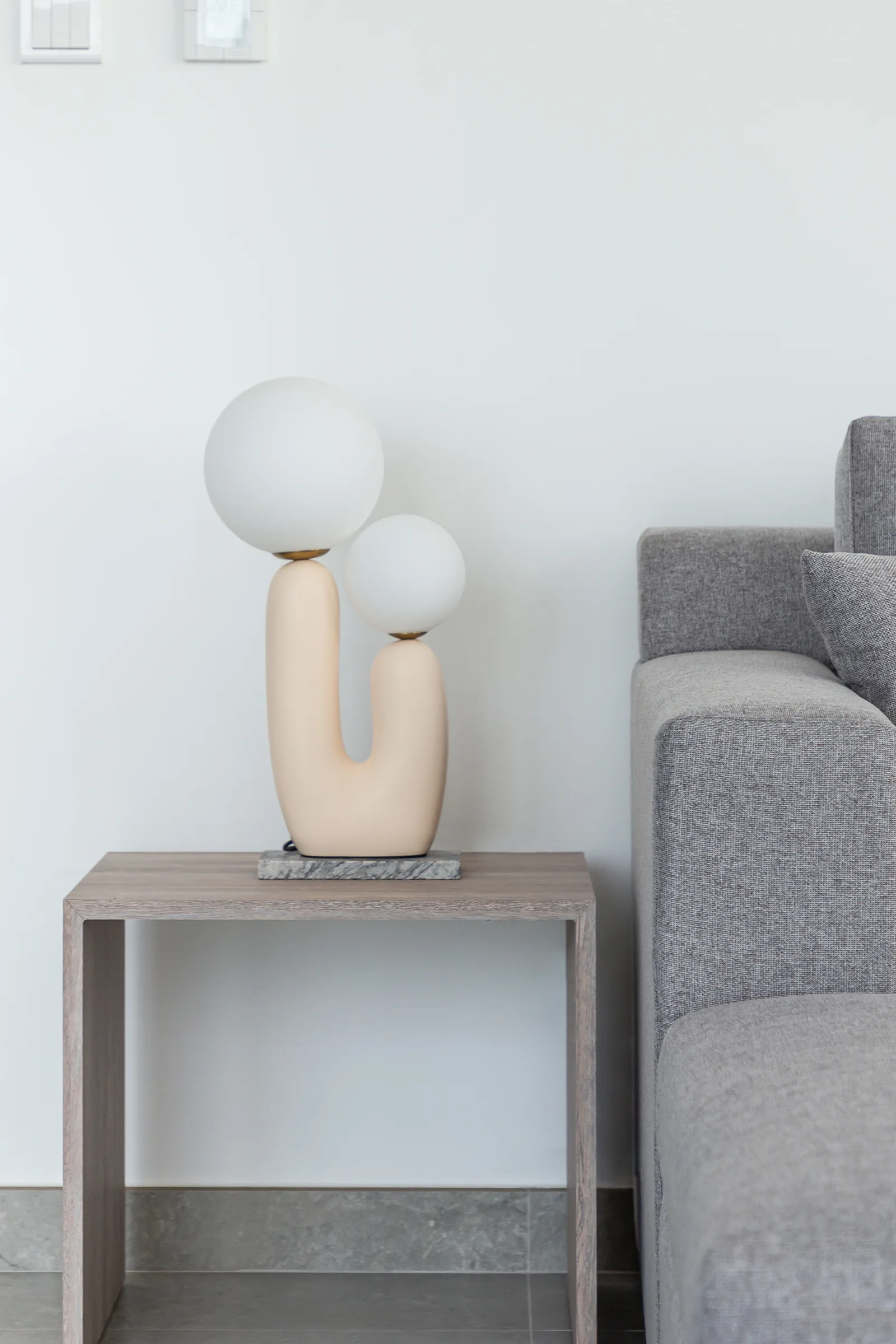 Sculptural two-globe table lamp and timber-toned side table.