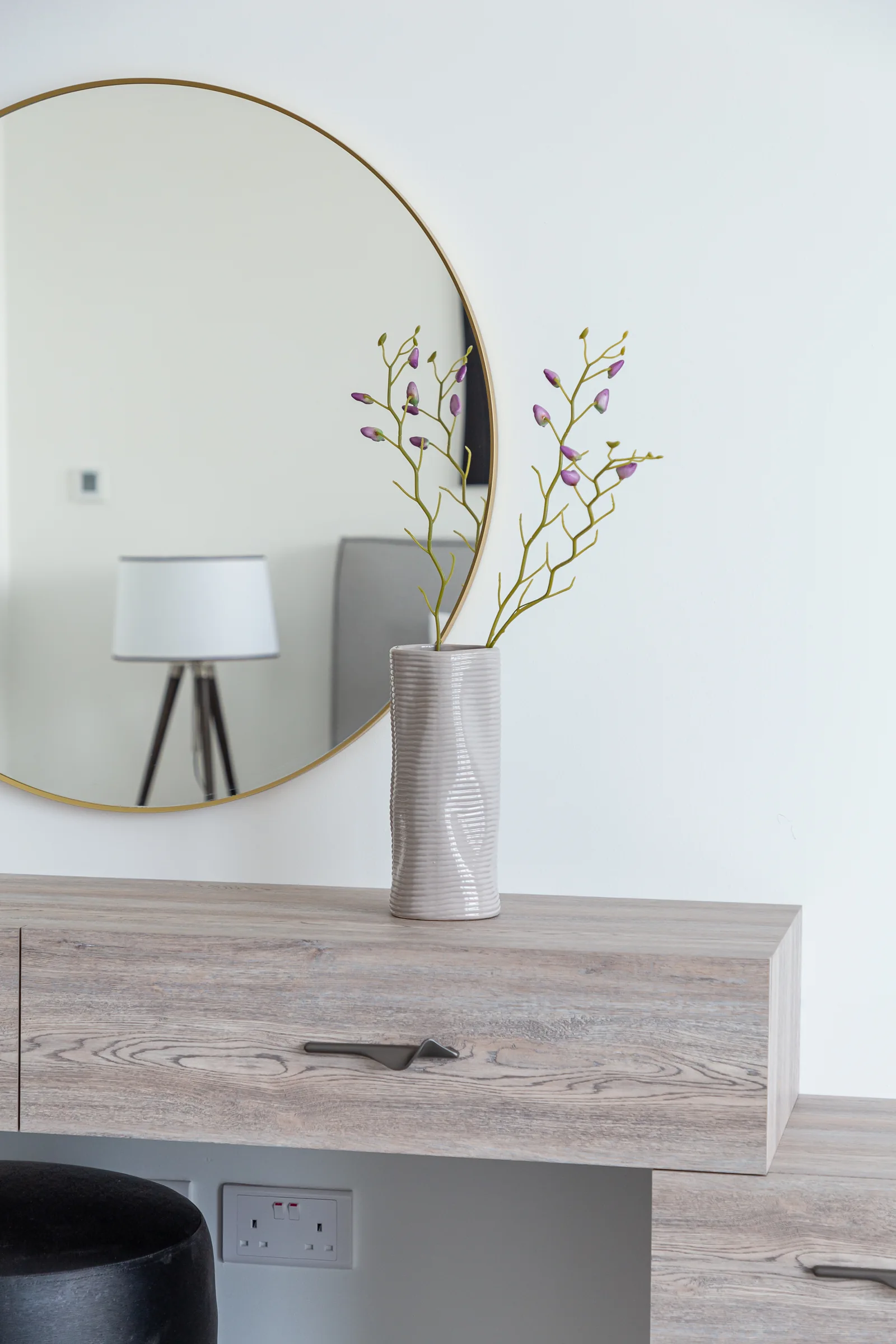 Timber-toned vanity drawer and round mirror.