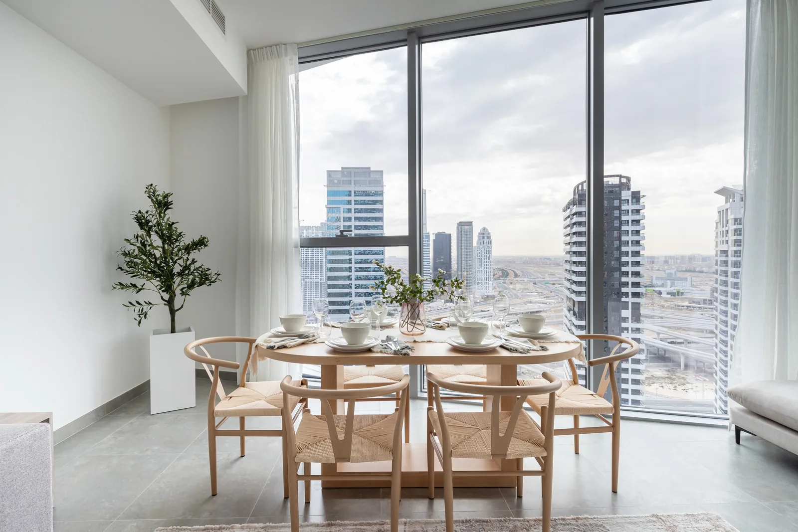 Timber-toned dining table, woven chairs and full-height windows.