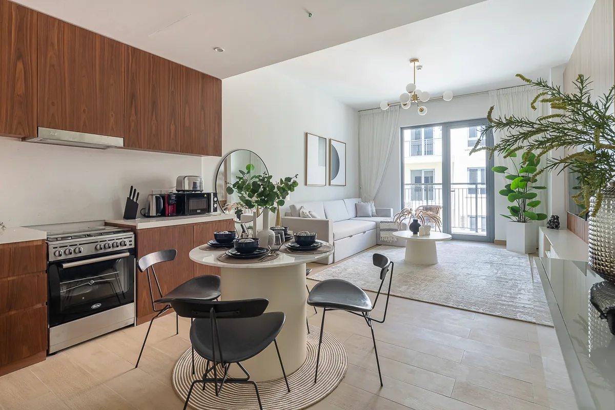 Round dining table between the kitchen and pale living-room seating.