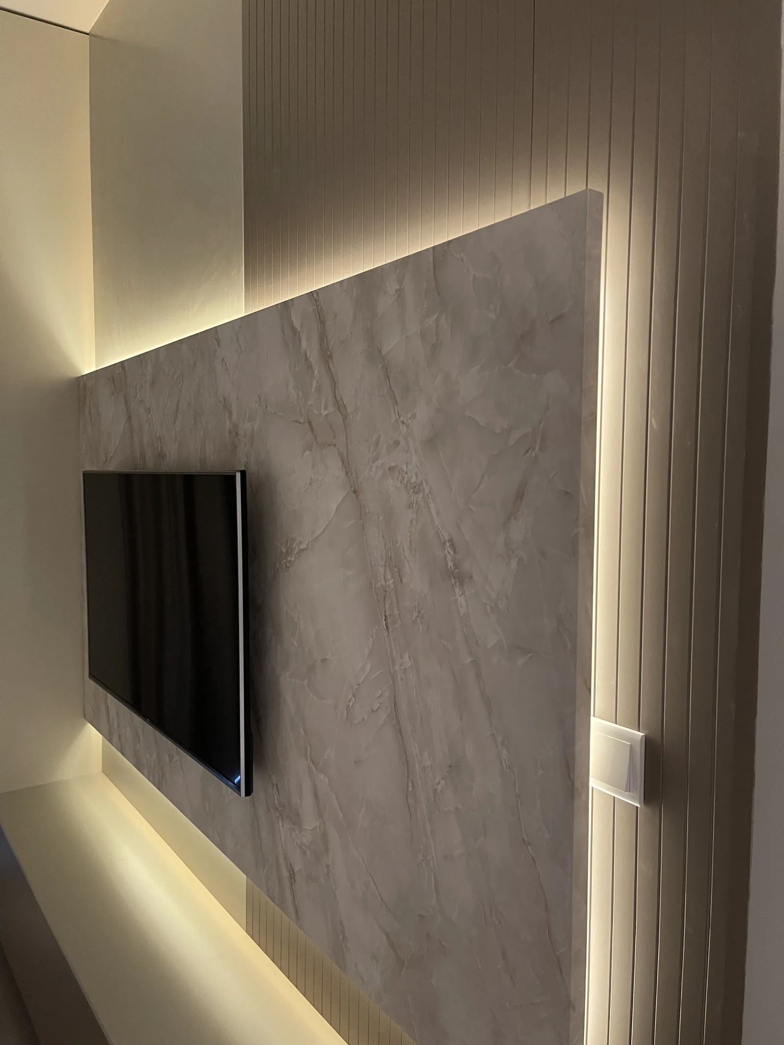 Light running around the edge of the veined TV panel against a grooved backing.