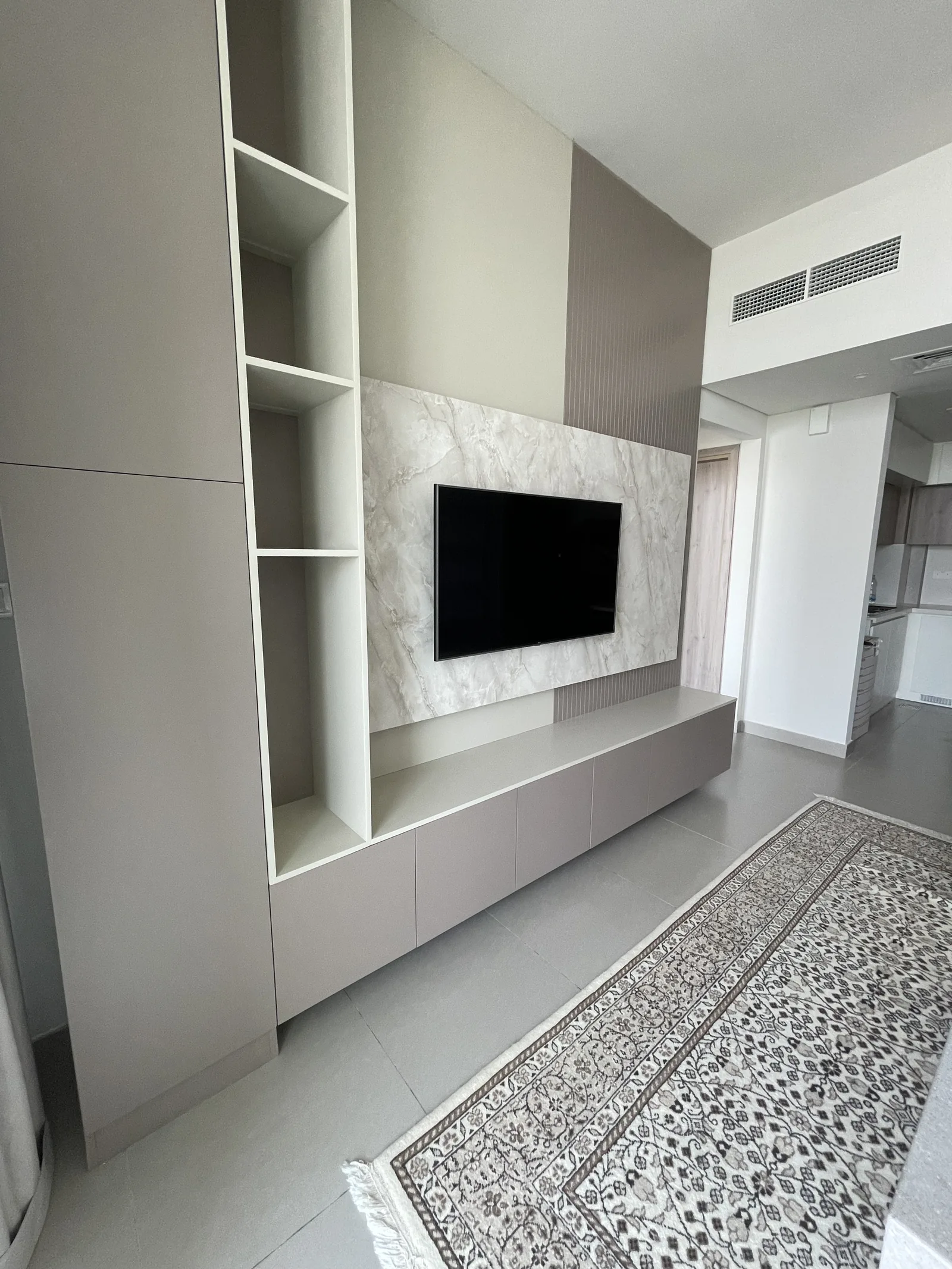 Angled view of the TV wall, tall open shelving and low cabinet run.