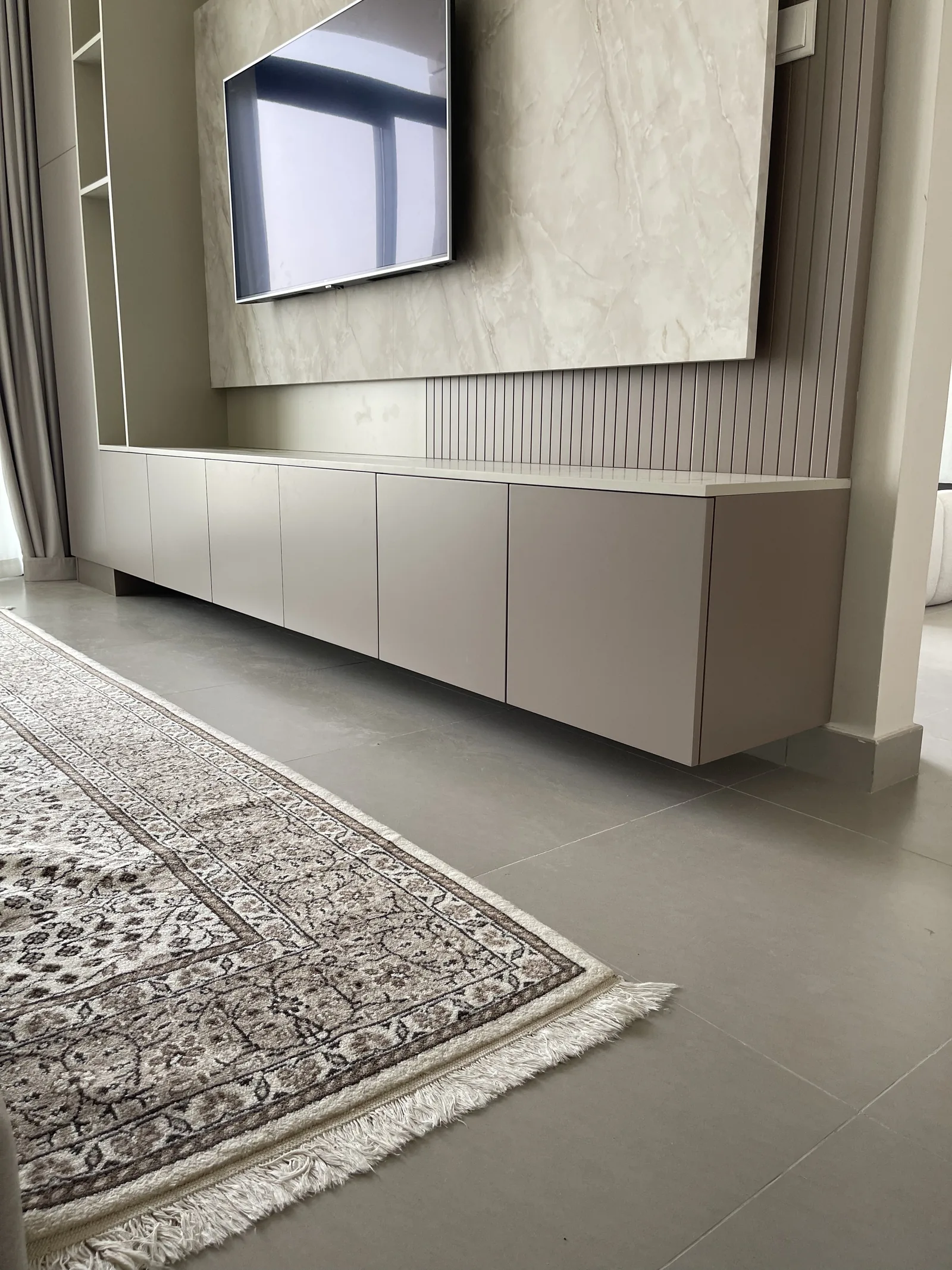 Low handle-free cabinet meeting the grooved wall panel behind the TV.