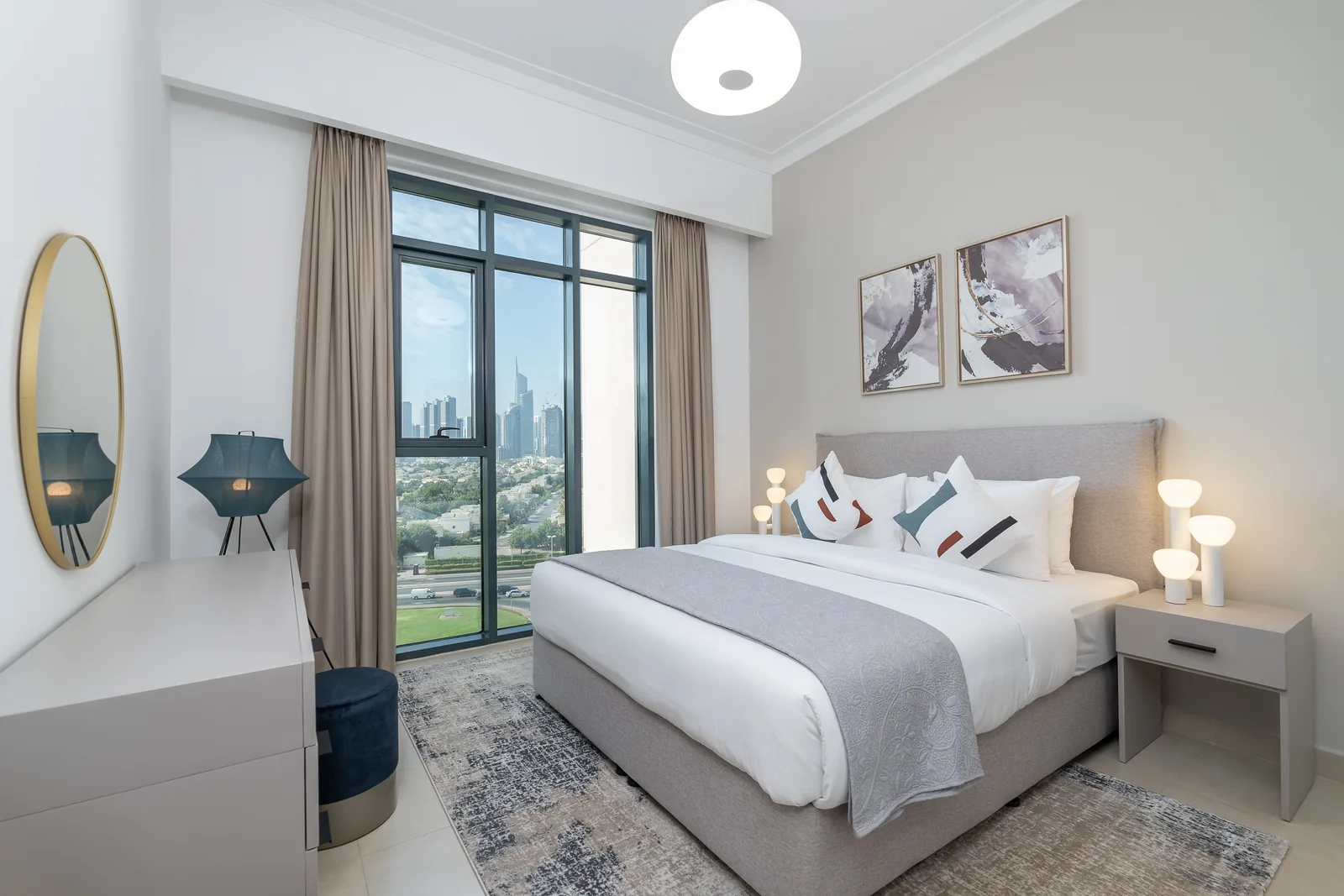 Grey upholstered bed with pale bedside furniture and blue accents.