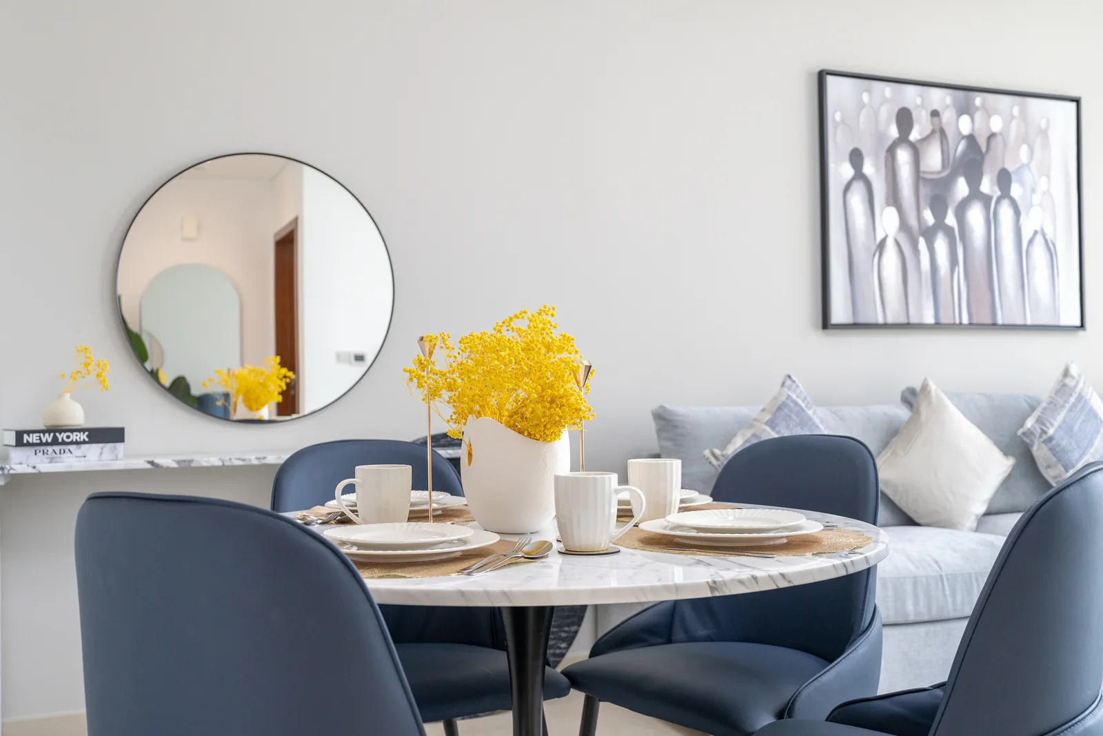 Round patterned dining table with deep-blue upholstered chairs.