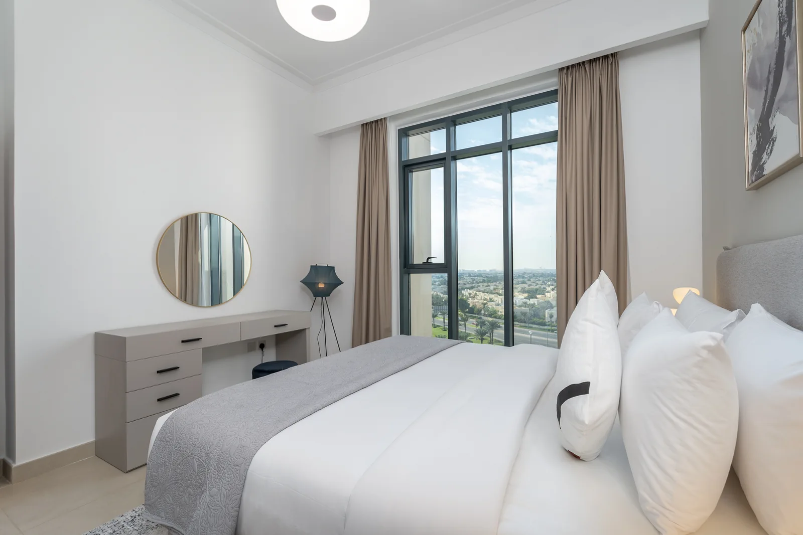 Reverse bedroom view toward dressing desk and full-height window.