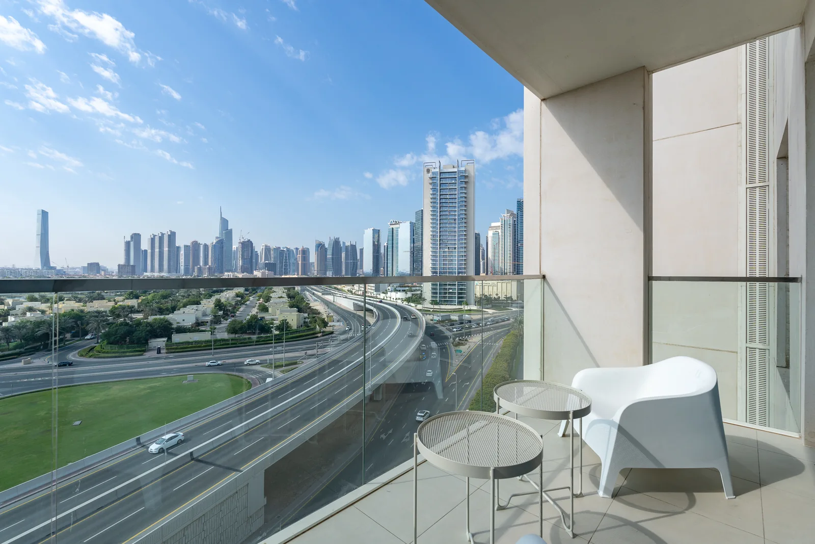 Apartment balcony seating and nesting tables with distant city backdrop.