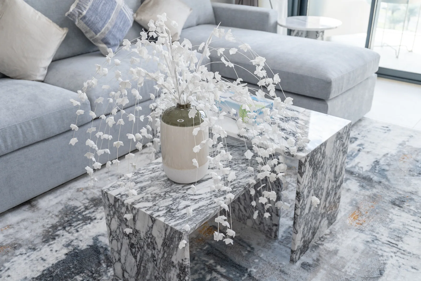 Patterned nesting coffee tables and white floral arrangement.