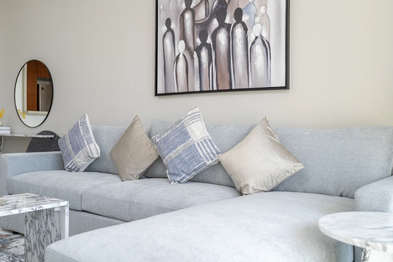Sectional upholstery, layered cushions and pale patterned side table.