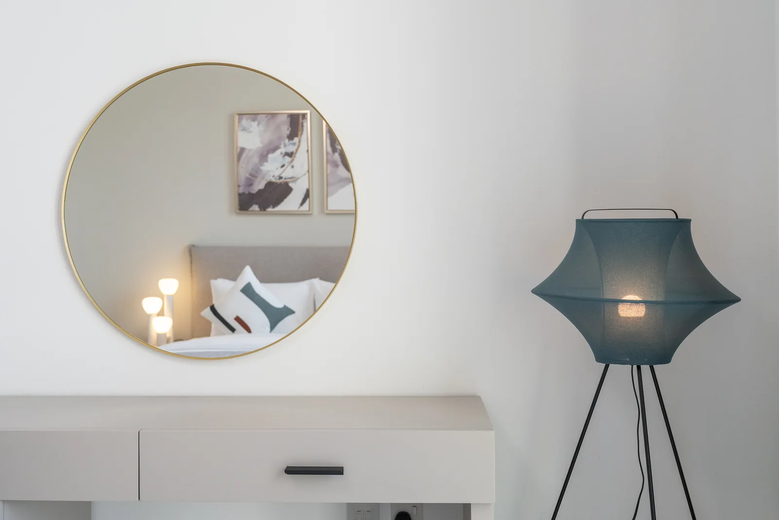 Dressing desk, round brass-toned mirror and blue sculptural floor lamp.
