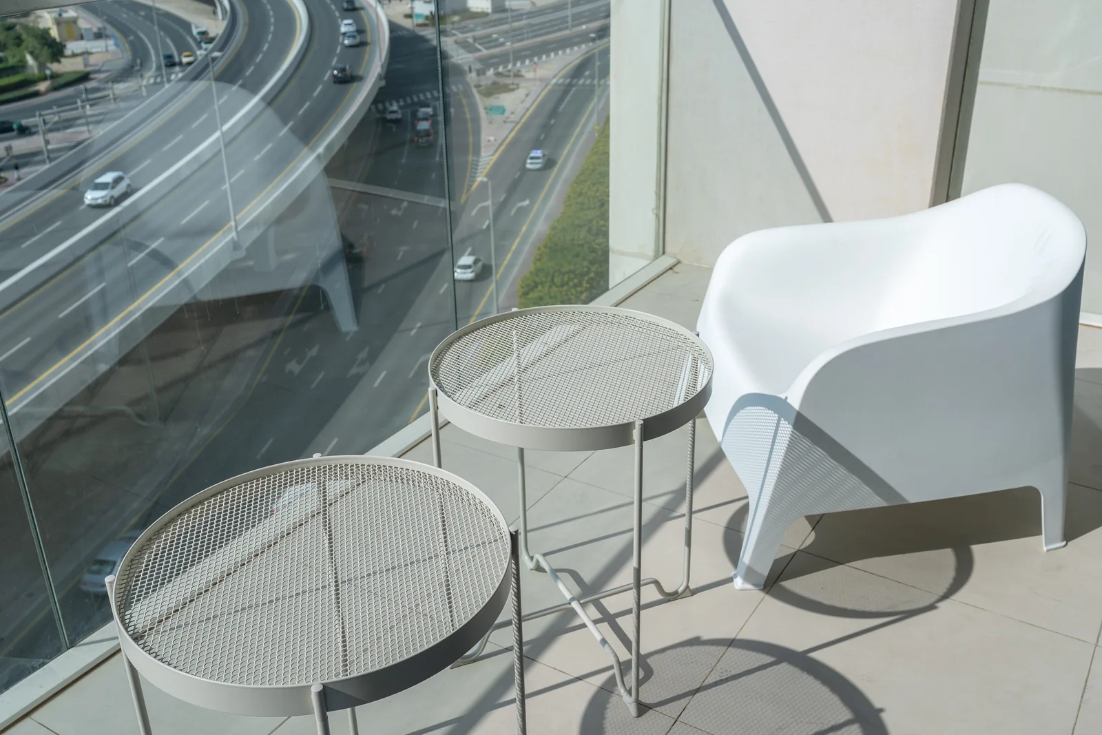 White balcony chair and paired mesh-top nesting tables.