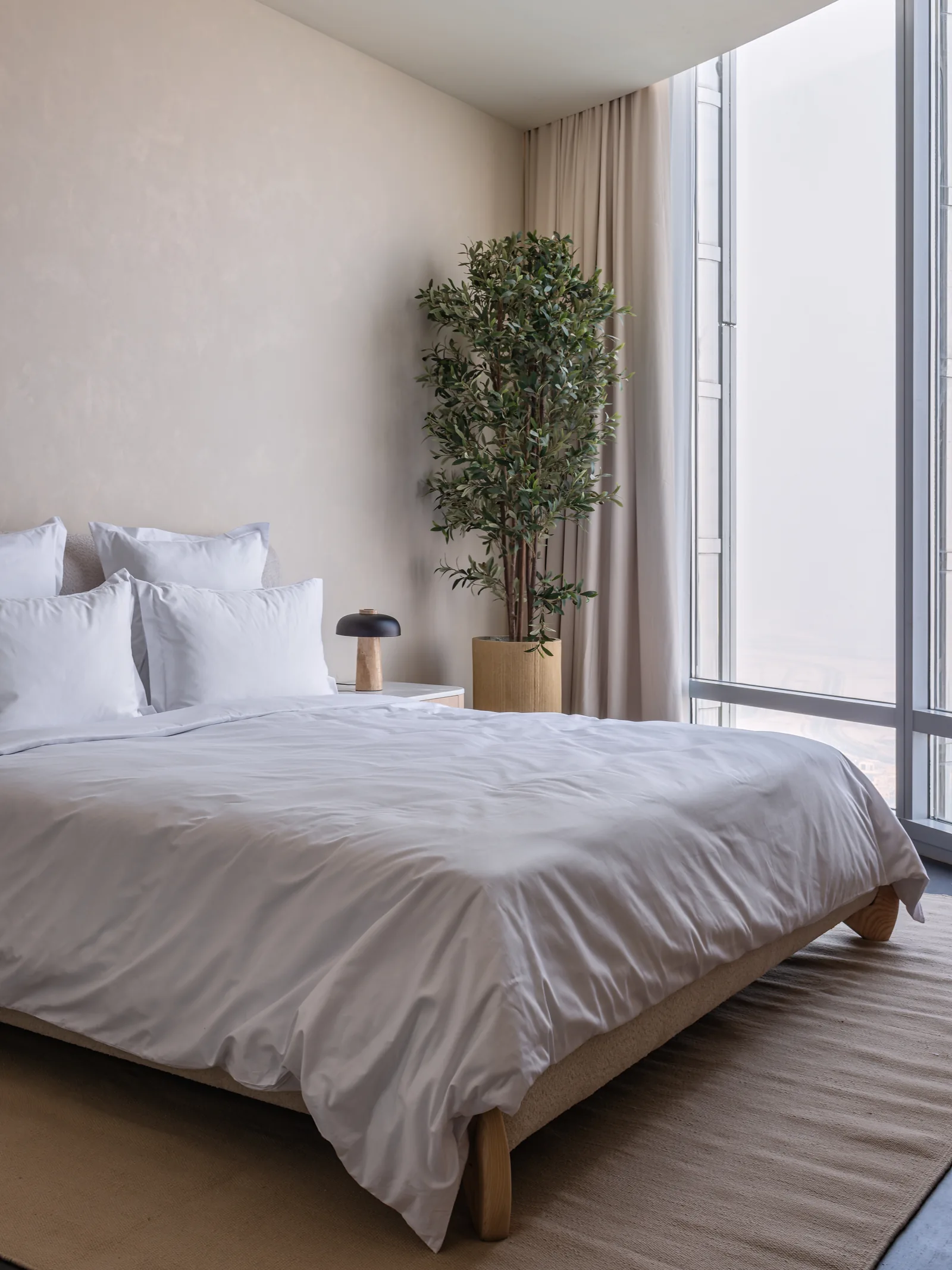 Neutral bedroom beside full-height glazing.