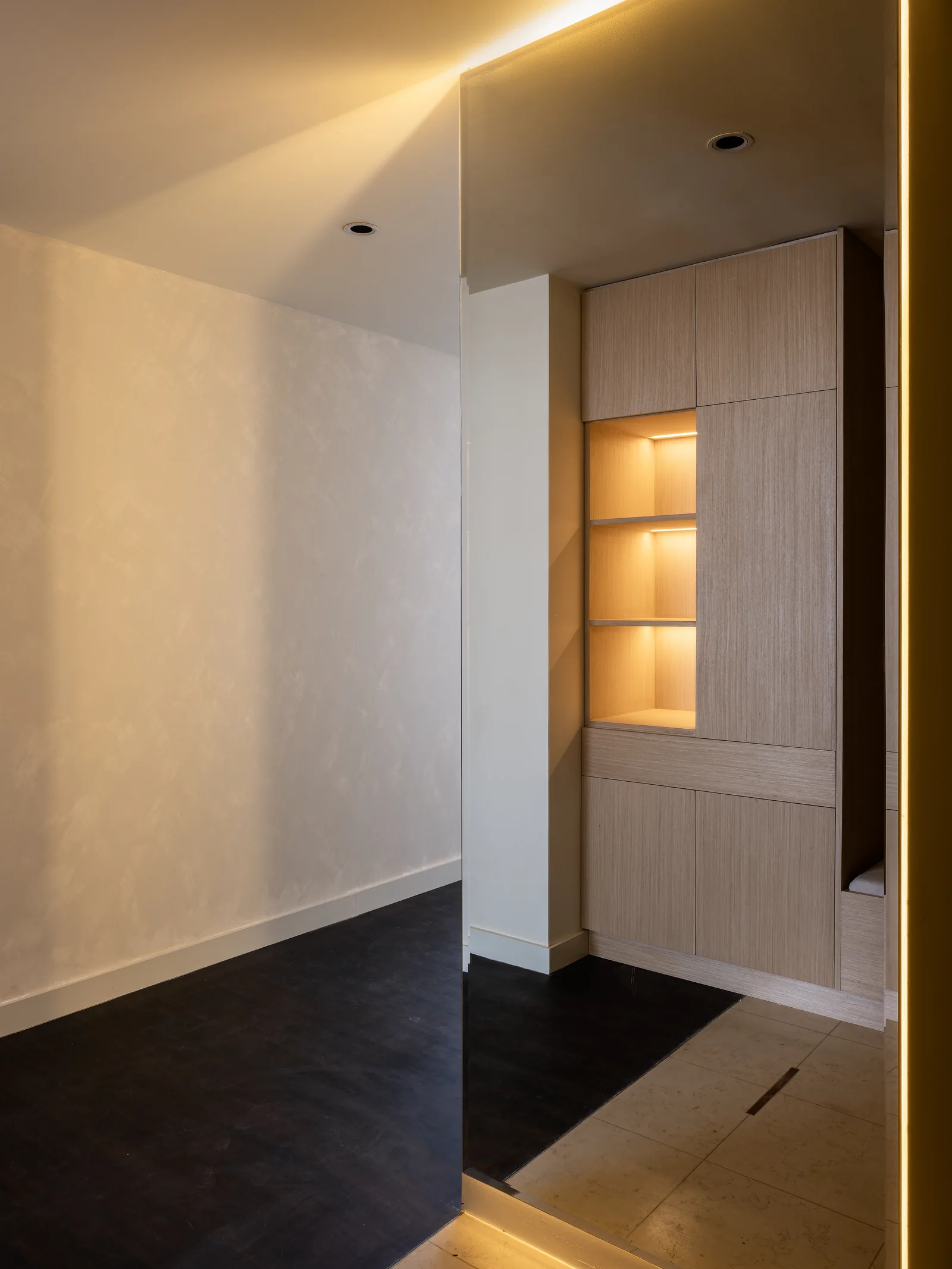 Illuminated mirror edge and timber-toned shelving.