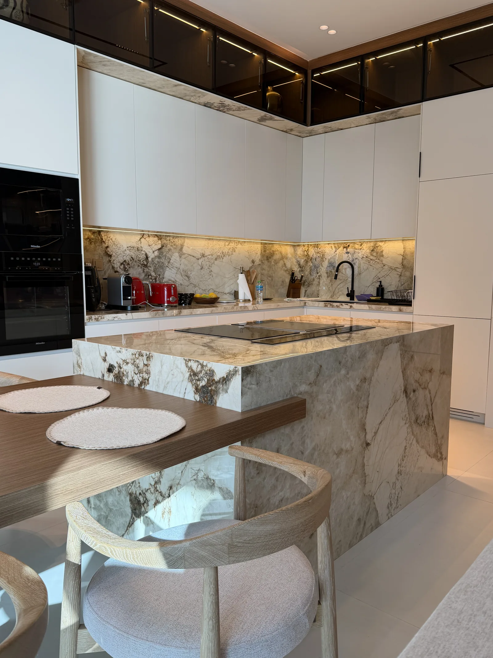 Reverse kitchen view with white cabinets, island and timber-toned dining extension.