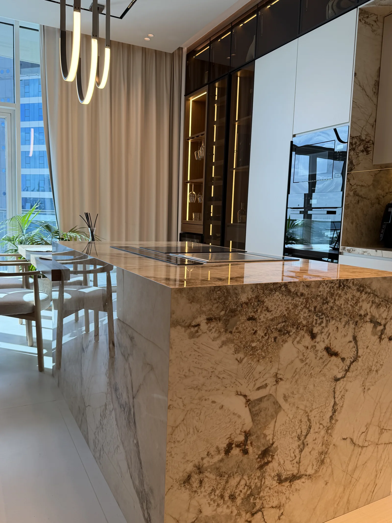 Close side view of veined waterfall island and inset cooktop.
