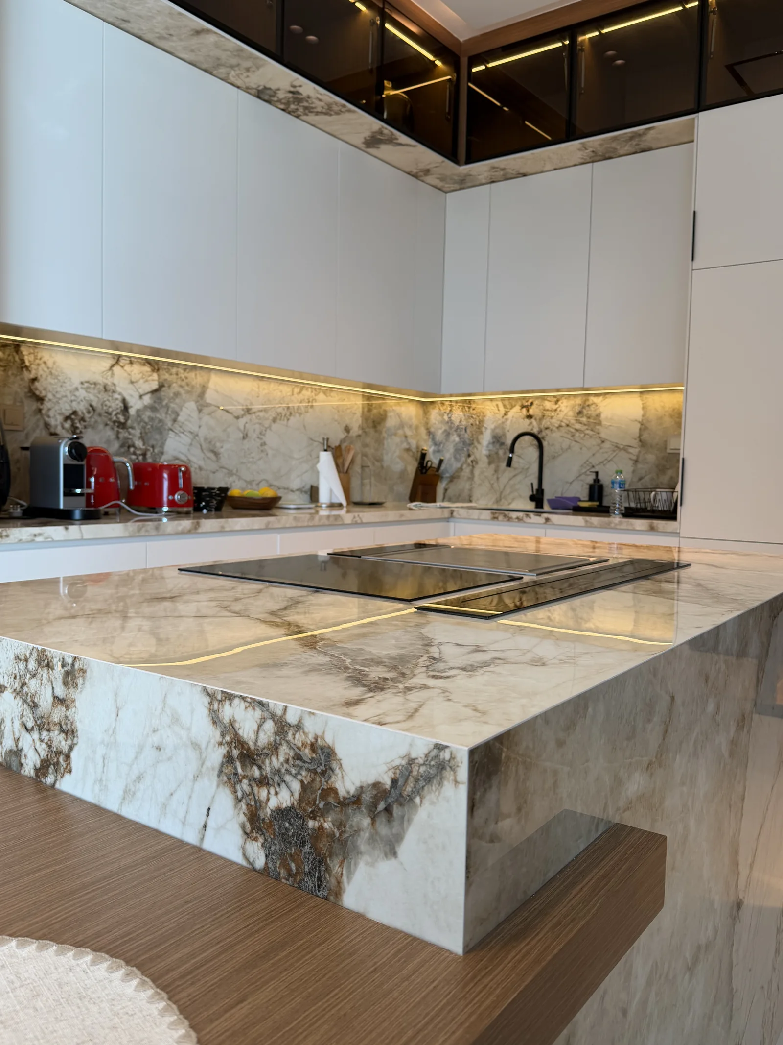 Worktop edge, cooktop and timber-toned table junction.