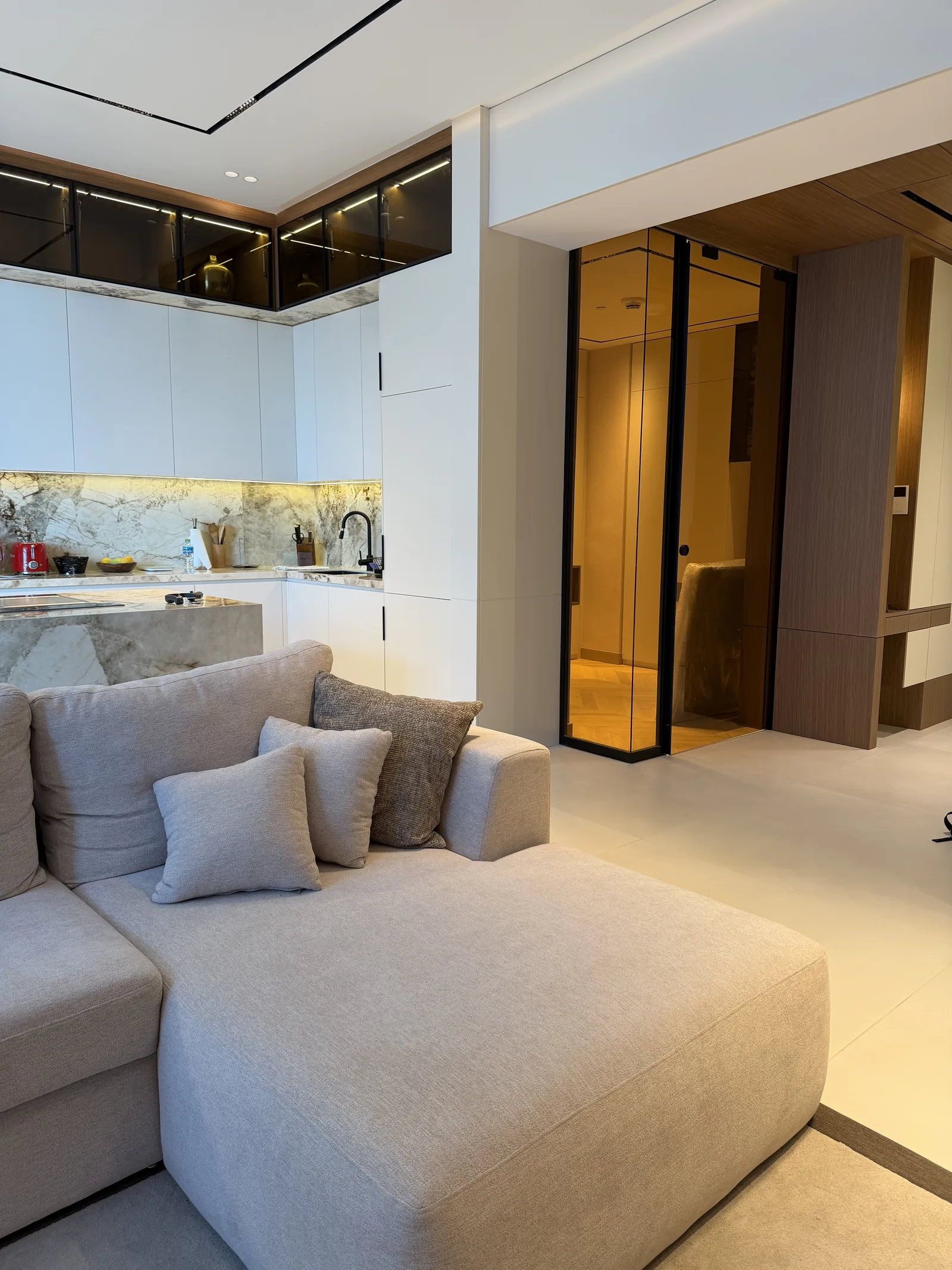 Pale chaise, kitchen cabinetry and amber glazed hallway divider.