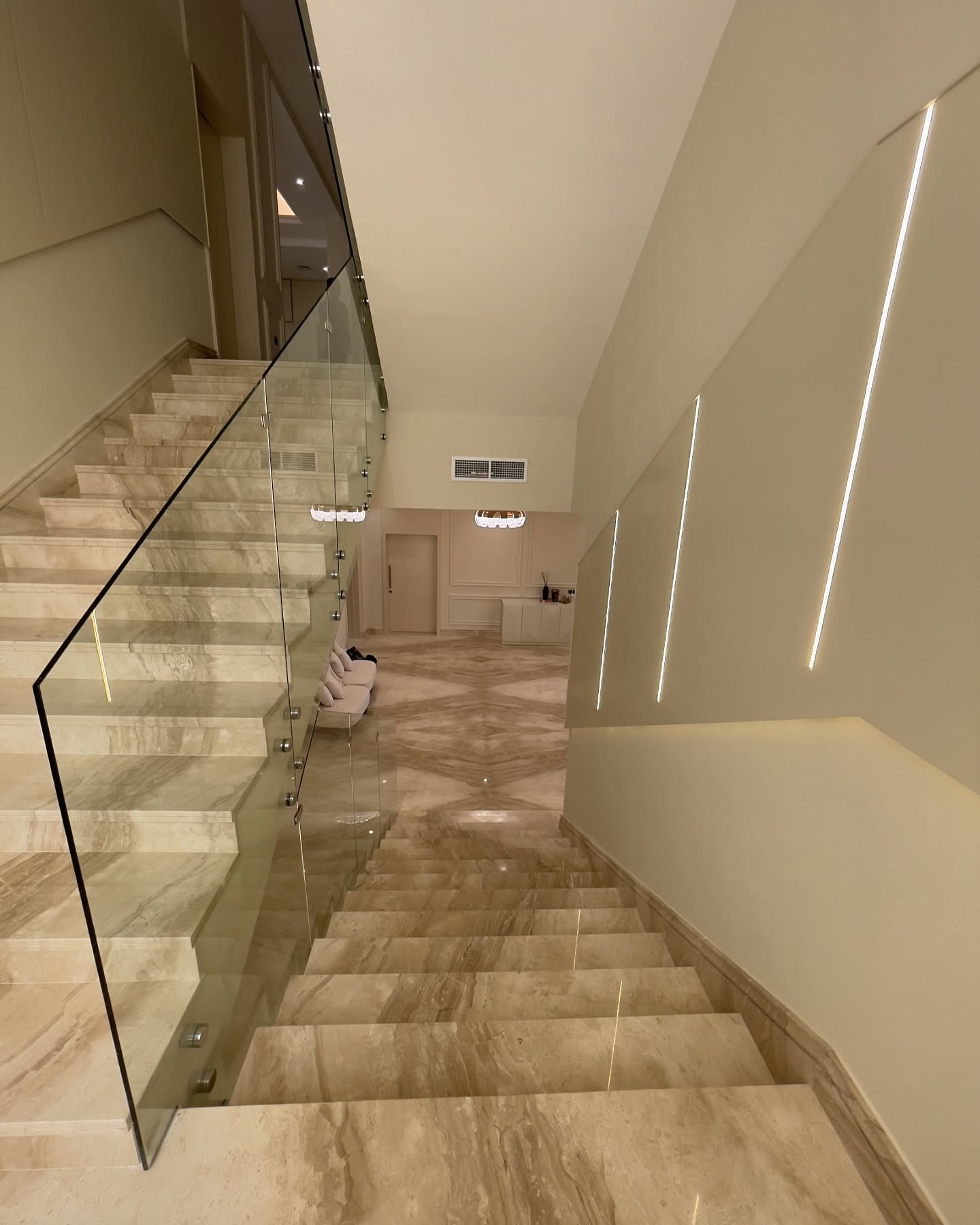 Angled staircase wall panels with integrated vertical lighting beside a glass balustrade.